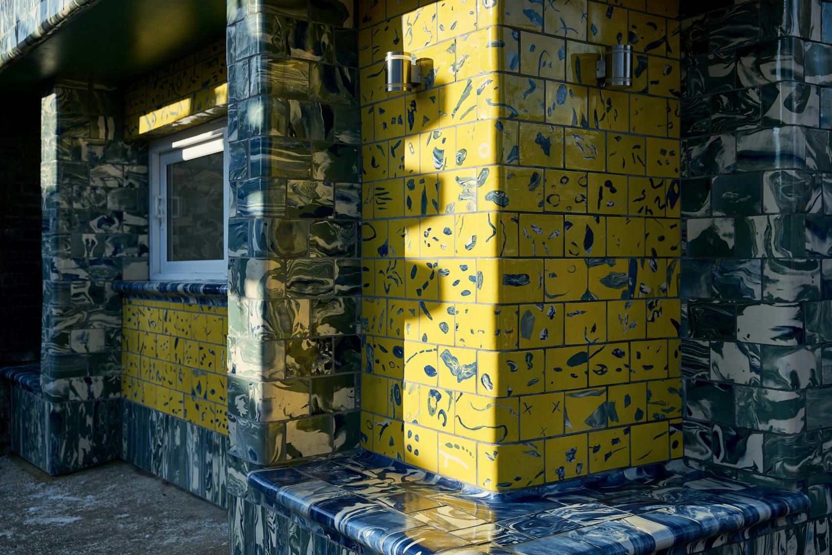 A detail showing handmade yellow and blue tiles on a transport kiosk