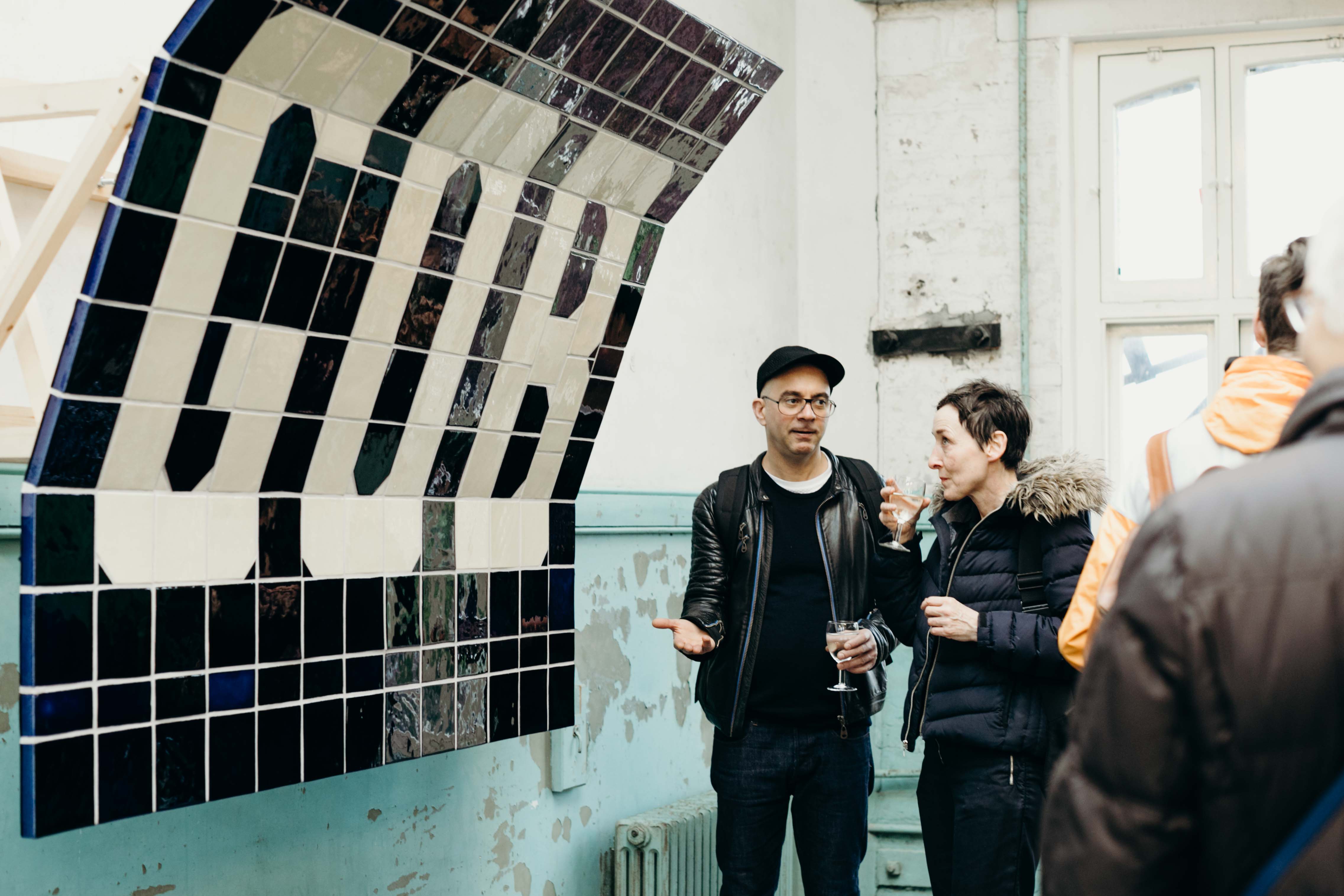 People standing below a tiled artwork that spells the letters G O B