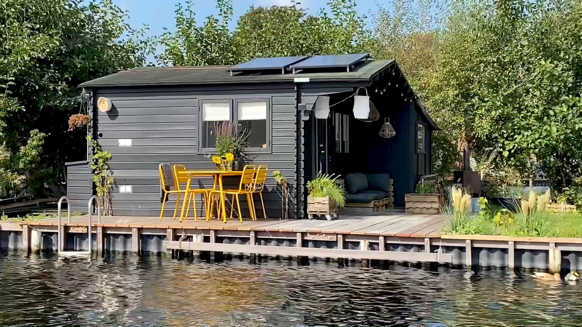 metalen tuinset Max okergeel tegen een zwart houten huisje op een eiland in de Vinkeveense plassen