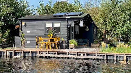 metalen tuinset Max okergeel tegen een zwart houten huisje op een eiland in de Vinkeveense plassen