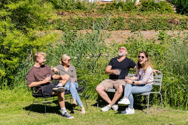 Mensen hebben plezier in de zon op tuinbanken van MaximaVida