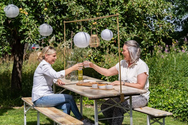 Zwei Personen prosten sich an dem klappbaren Picknicktisch Berlin whitewash