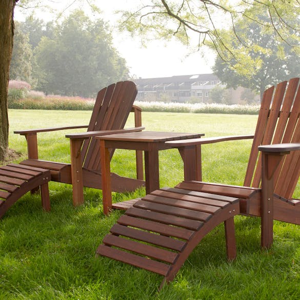 Adirondack set; twee stoelen met voetenbankjes en een tafeltje in de tuin 