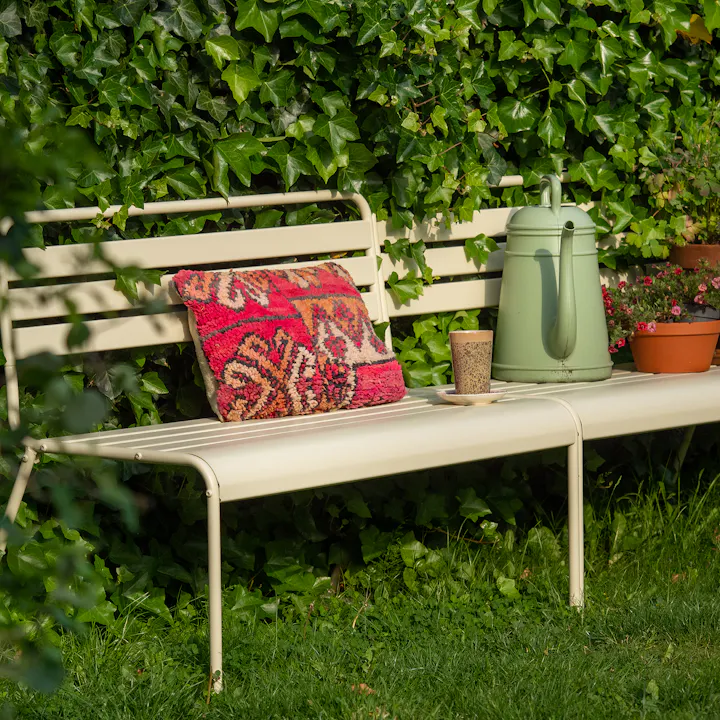 Elfenbeinfarbene metall-gartenbank Max mit kissen und pflanzen
