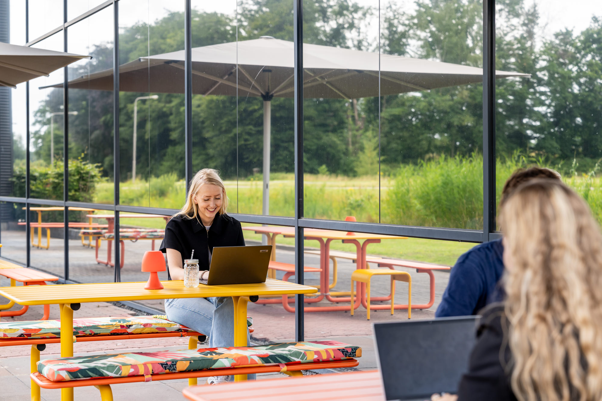Gekleurde metalen picknicktafels bij kantoorpand buiten op terras