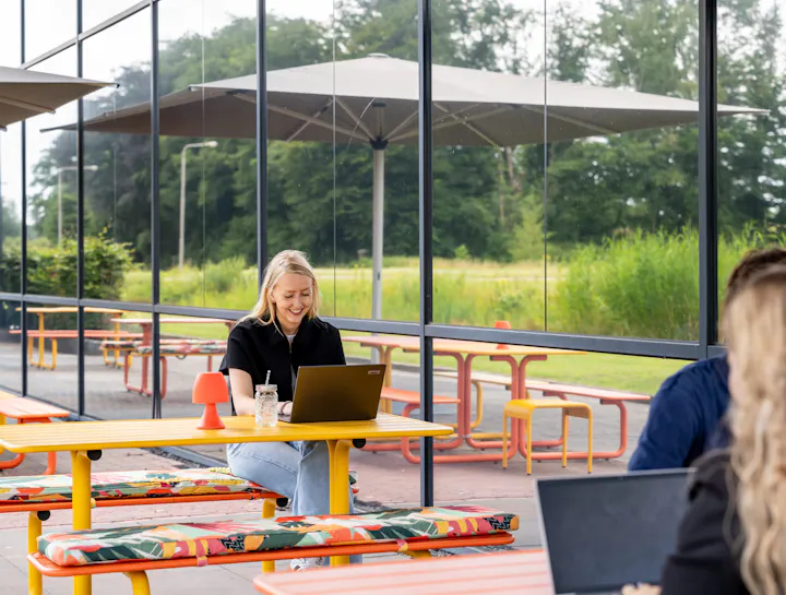 Gekleurde metalen picknicktafels bij kantoorpand buiten op terras