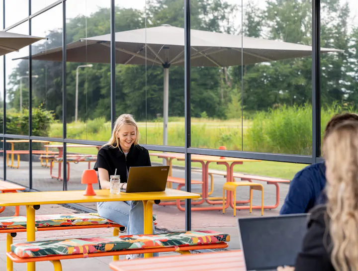 Coloured metal picnic tables on the terrace outside the office building