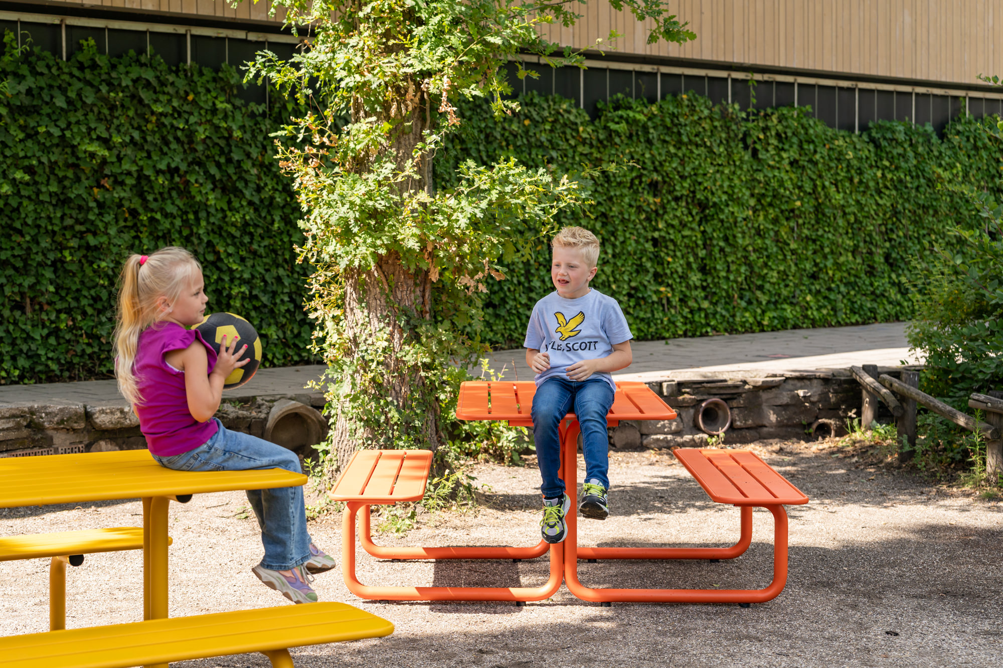 Spielende Kinder an bunten Picknicktischen aus Metall