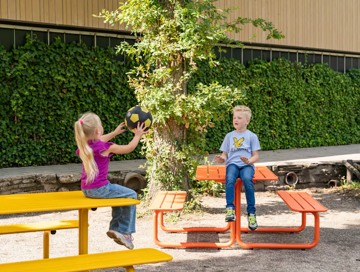 Children playing at colourful metal picnic tables