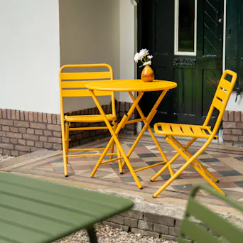 Ochre-yellow Max bistro set on the terrace in front of the house