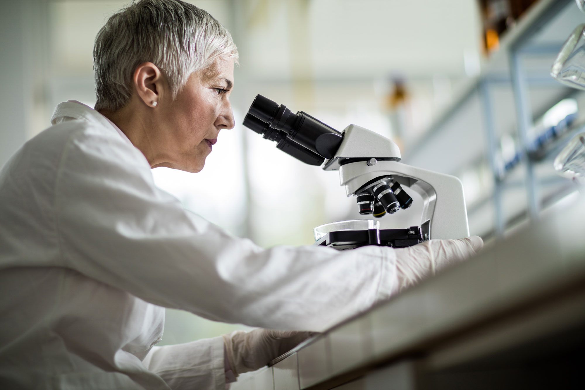 Wissenschaftlerin schaut durch ein Mikroskop