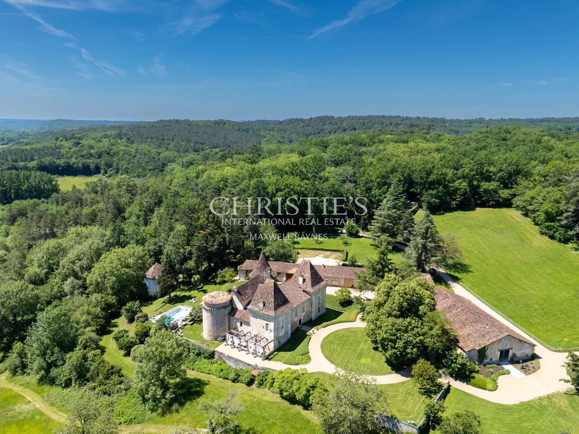 Aerial view of a historic Dordogne château with swimming pool, outbuildings and extensive grounds