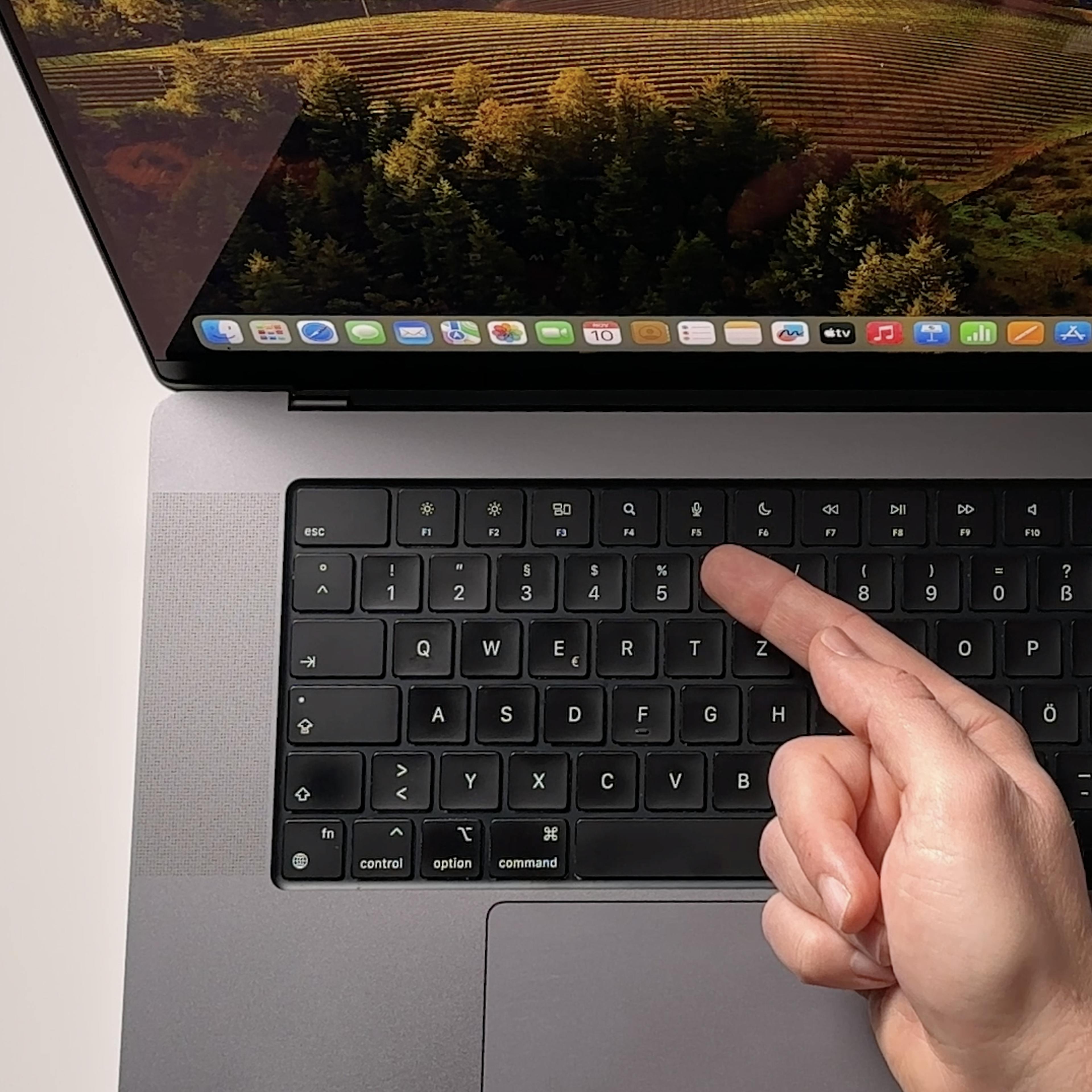 Hand zeigt auf Macbook Tastatur