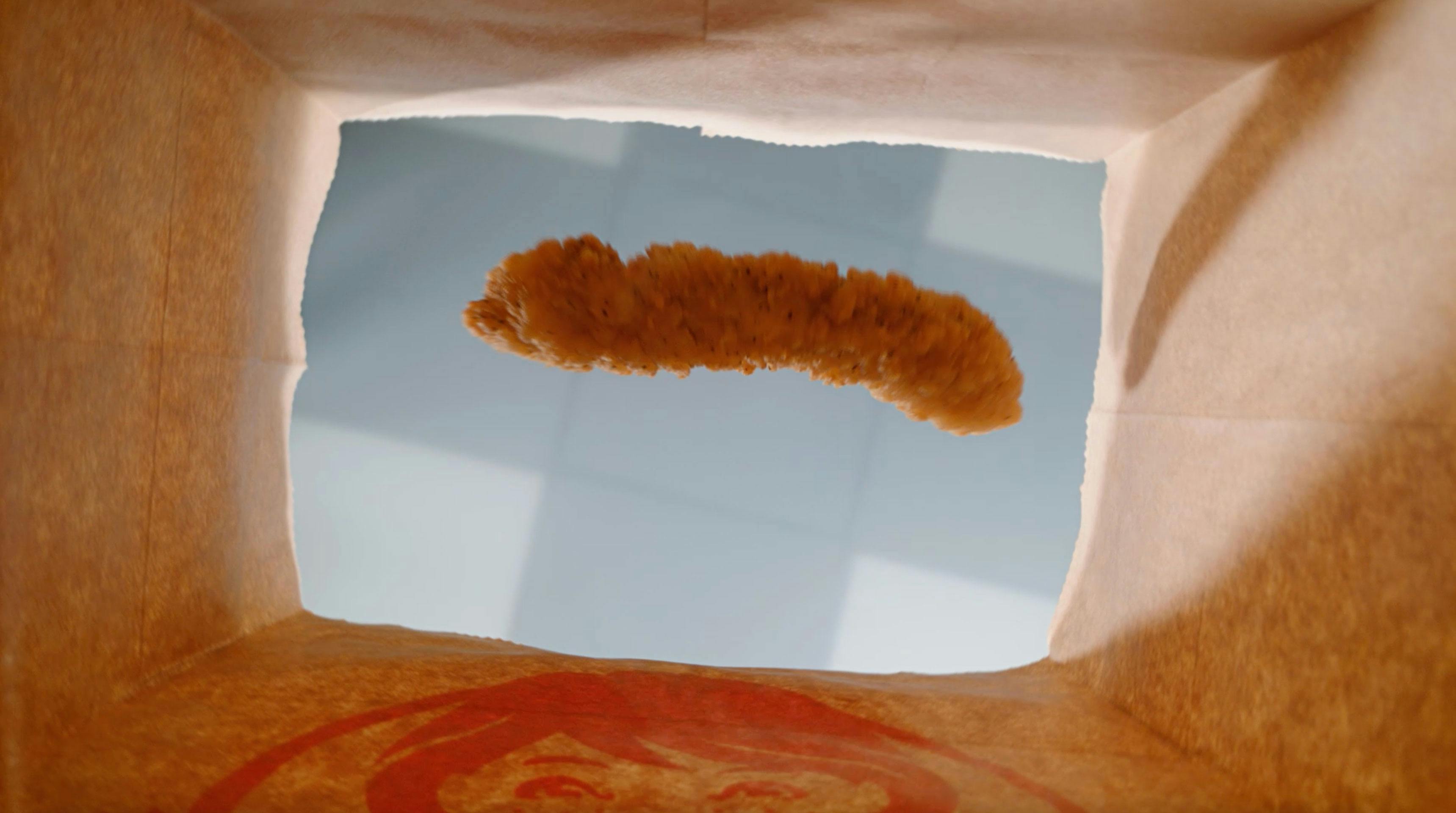 Wendy's chicken strip being dropped in a paper bag.