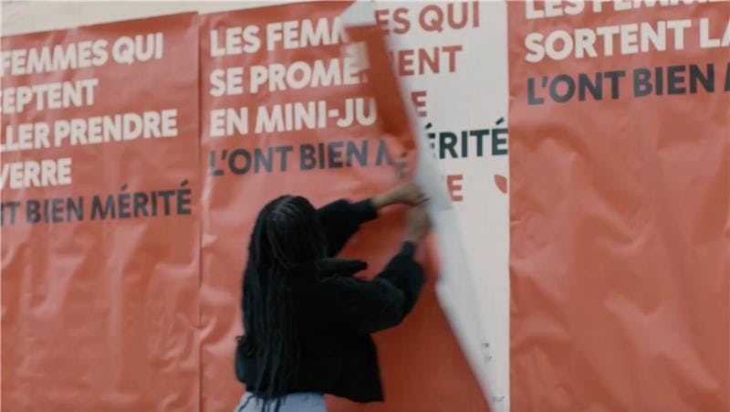 woman ripping down posters from a billboard.