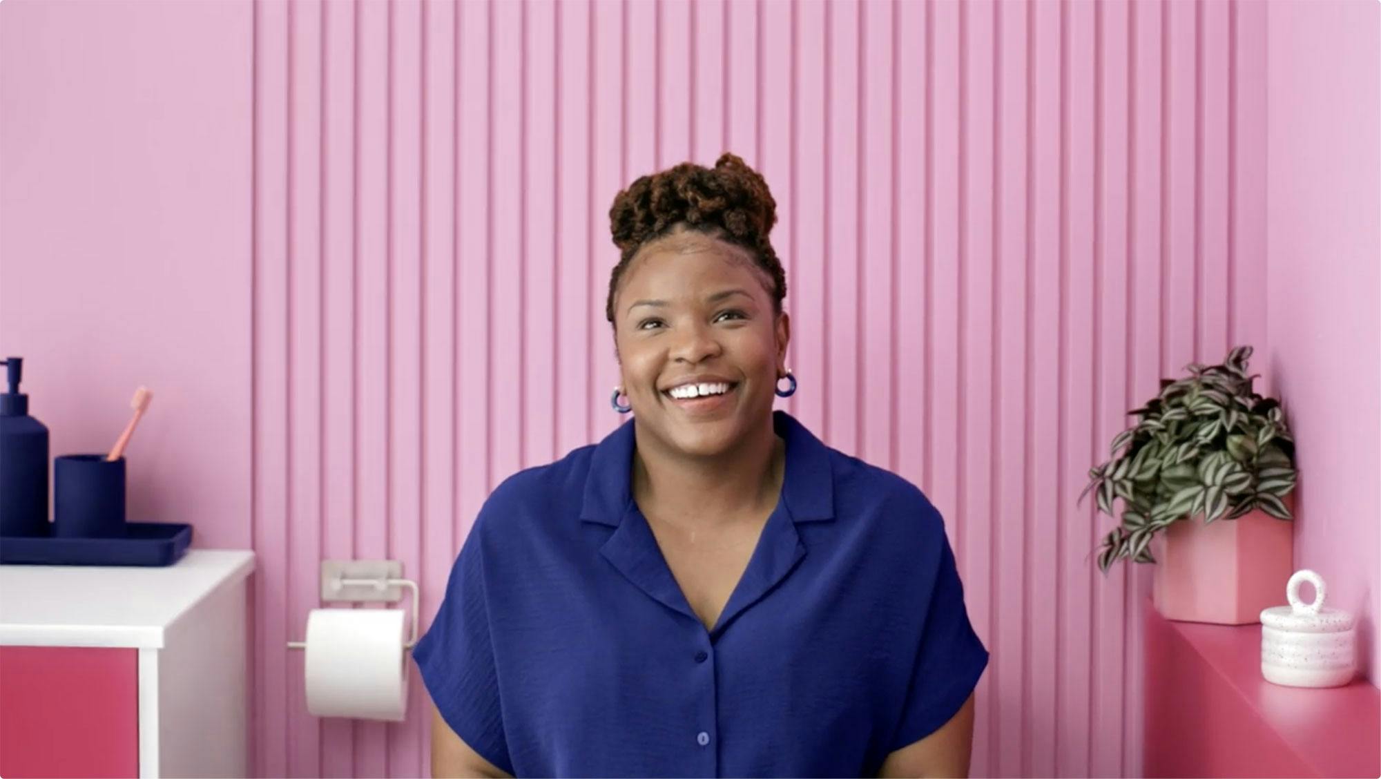 Woman smiling infront of a pink wall