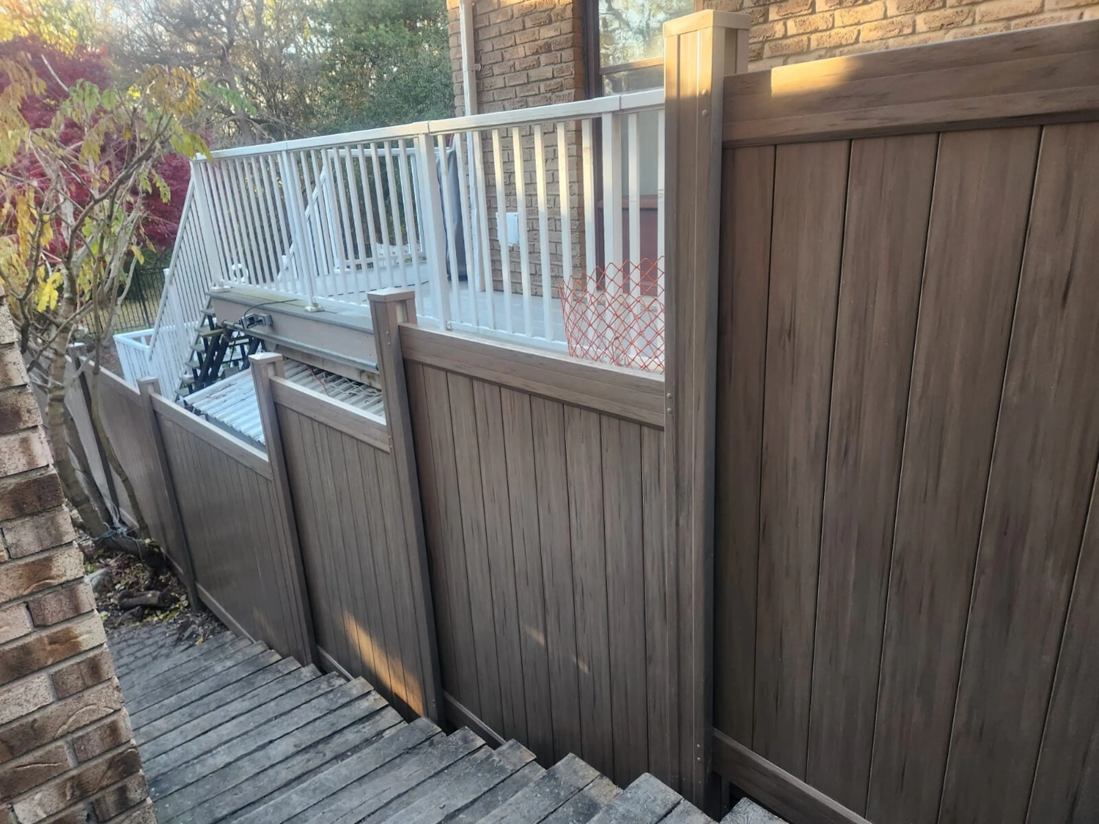 A brown vinyl fence next to a set of outdoor stairs in a residential backyard.