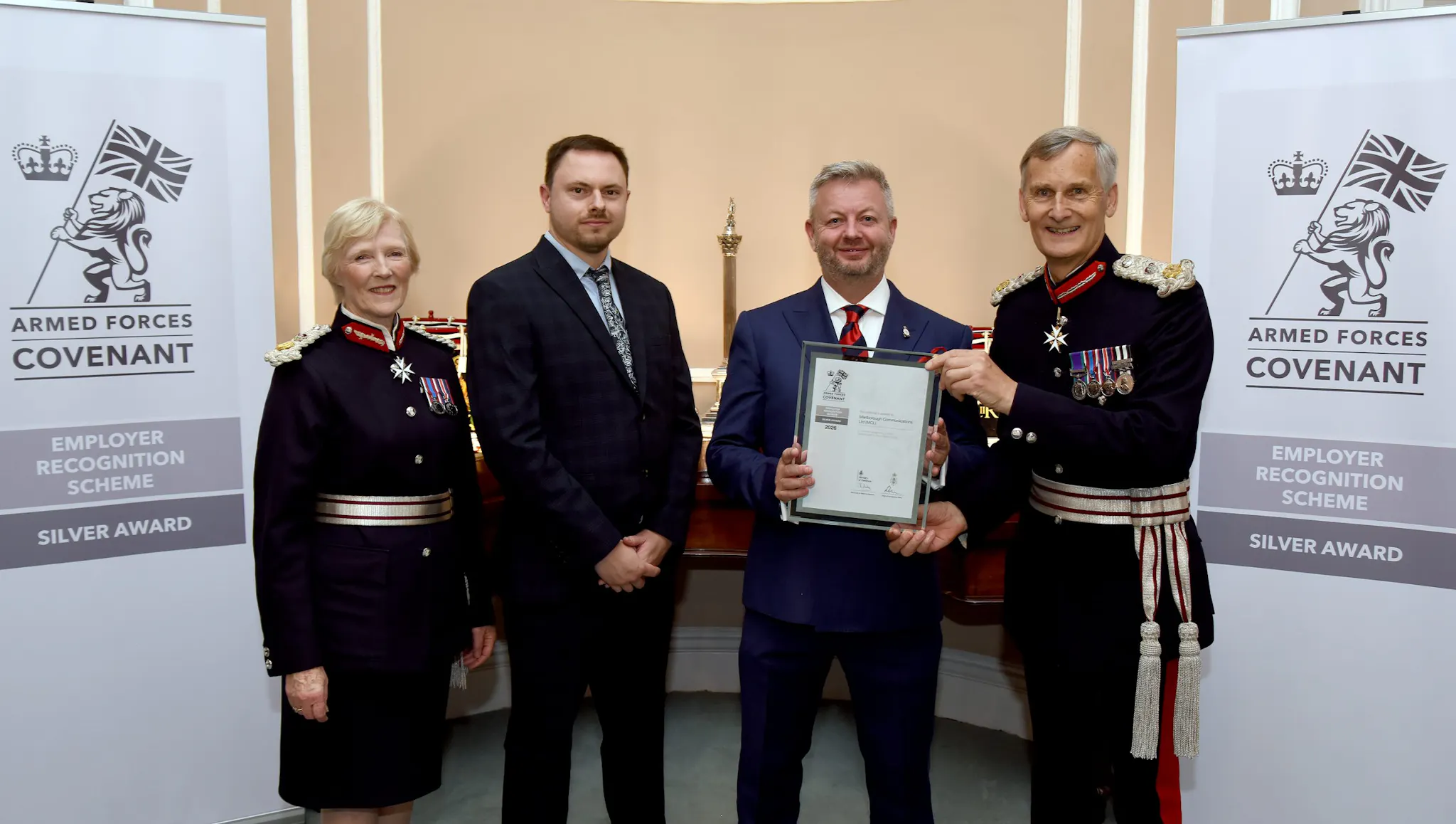 MCL representatives receiving the Ministry of Defence Employer Recognition Scheme Silver Award certificate at the South East ERS Awards 2026, pictured with a Lord-Lieutenant and Deputy Lord-Lieutenant in ceremonial uniform in front of Armed Forces Covenant Silver Award banners.