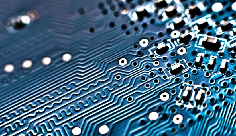  Close-up of a blue printed circuit board (PCB) showing intricate lines, pathways, and electronic components.