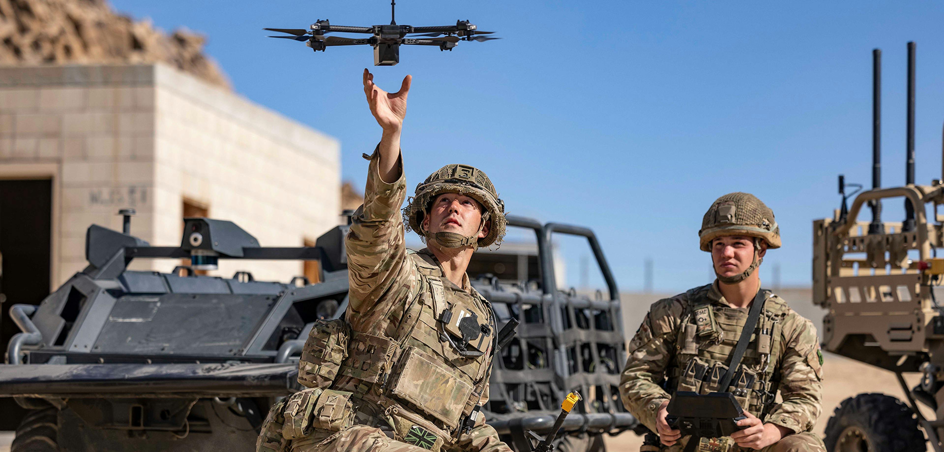 Two military men launching a small communications drone.
