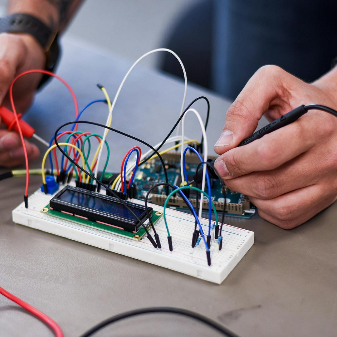 A close up of a persons' hands working on some electrical connections