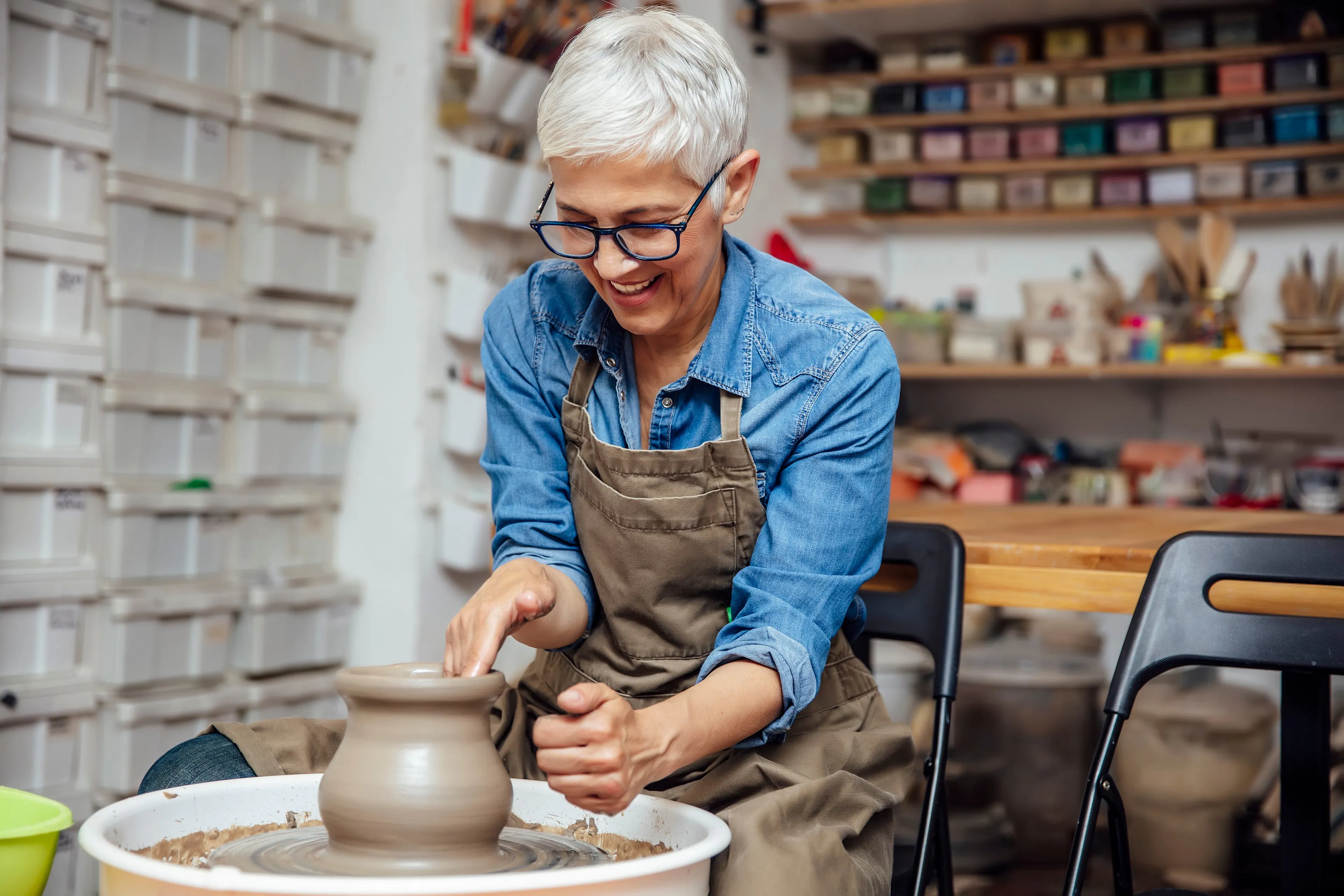 happy mature woman making clay pot