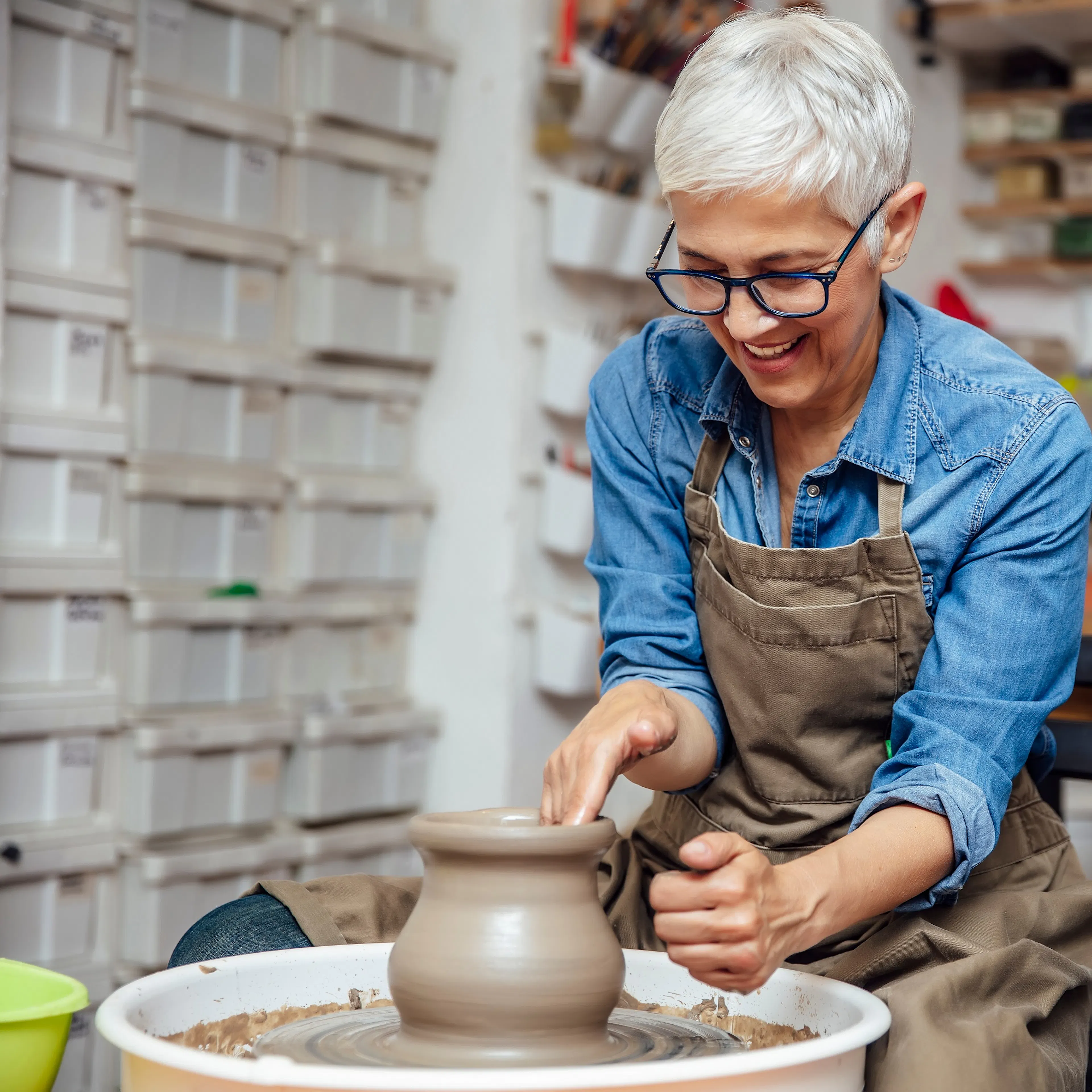 happy mature woman making clay pot