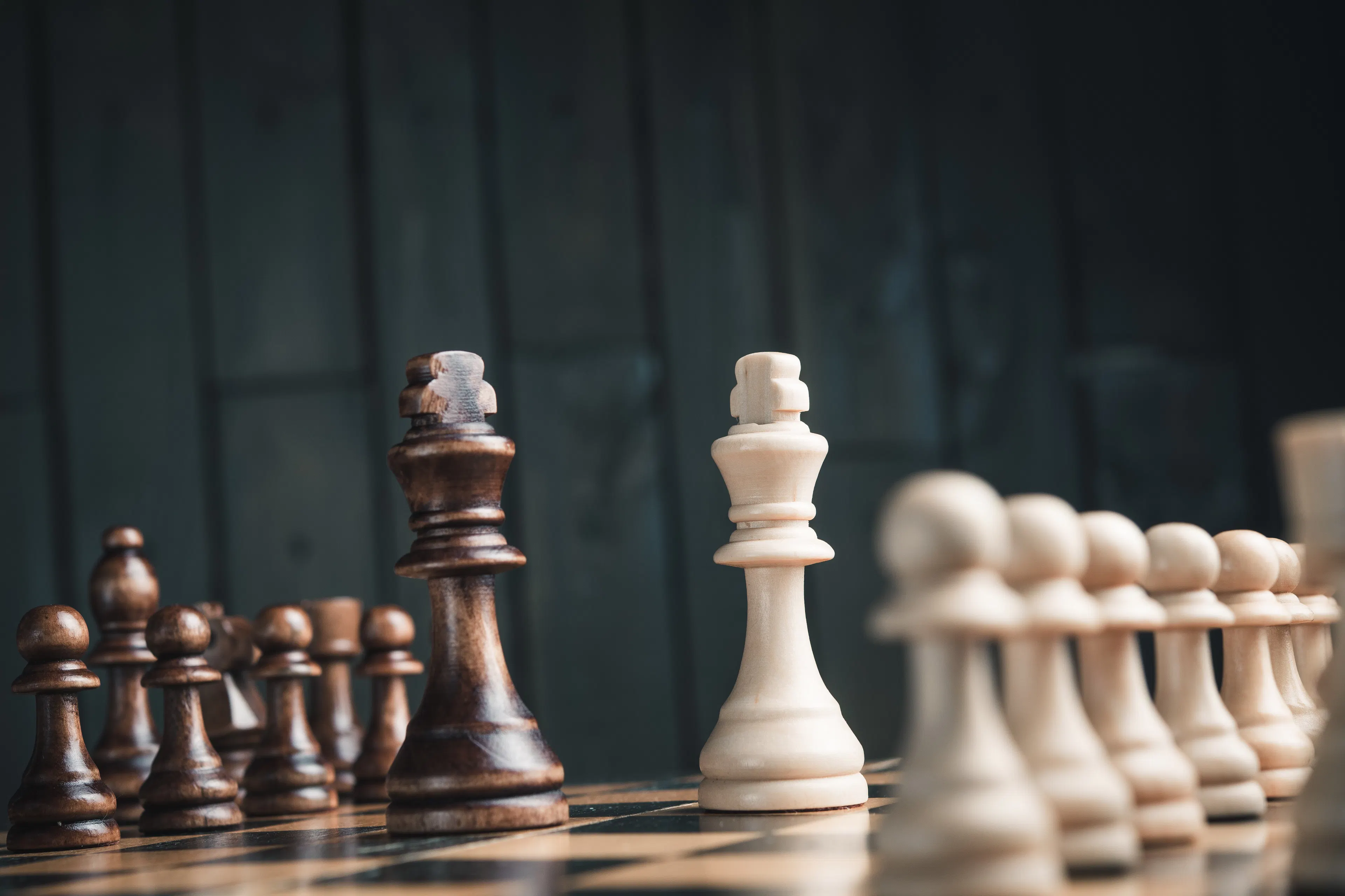 brown and white chess board with kings facing