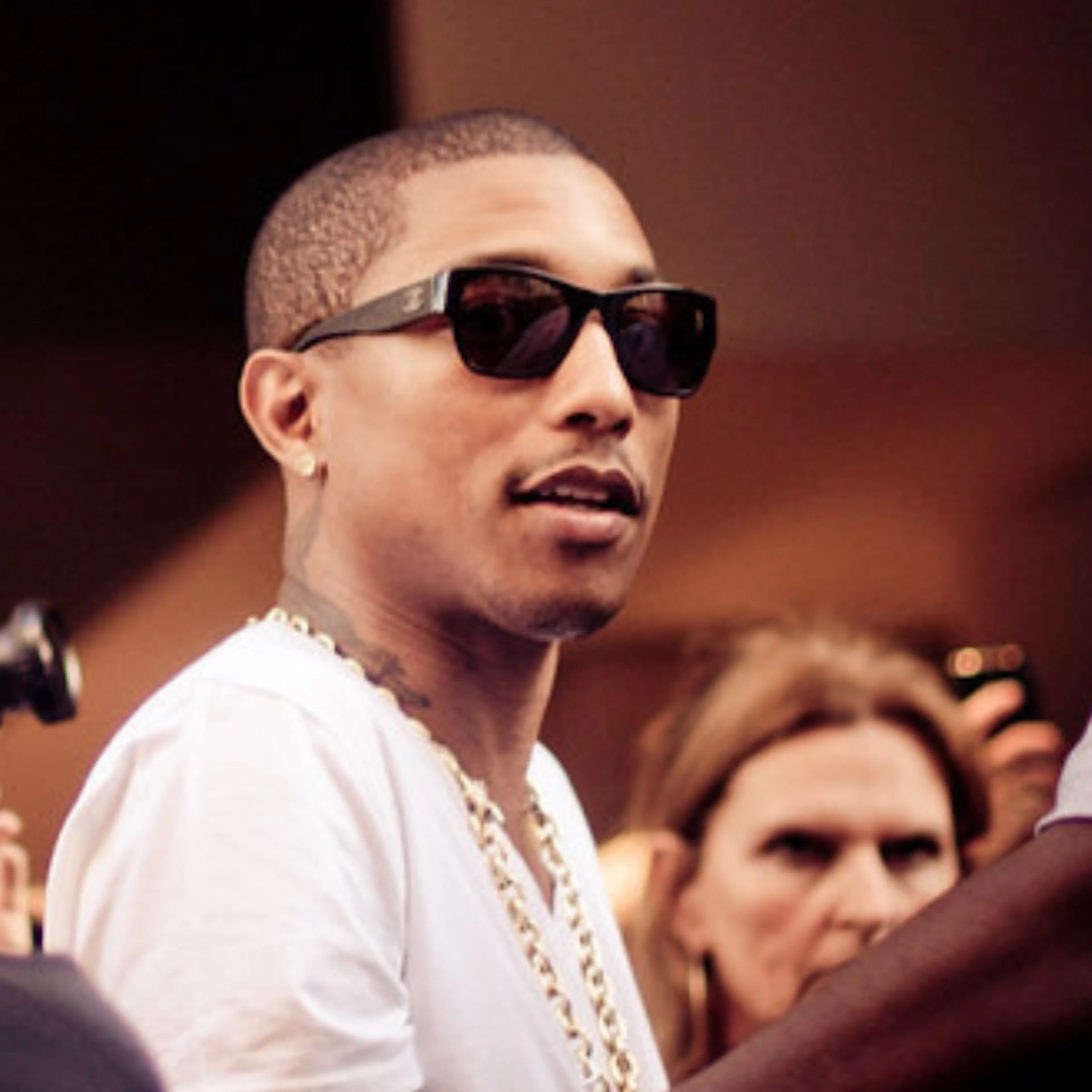 Pharrell Williams with sunglasses on surrounded by crowd