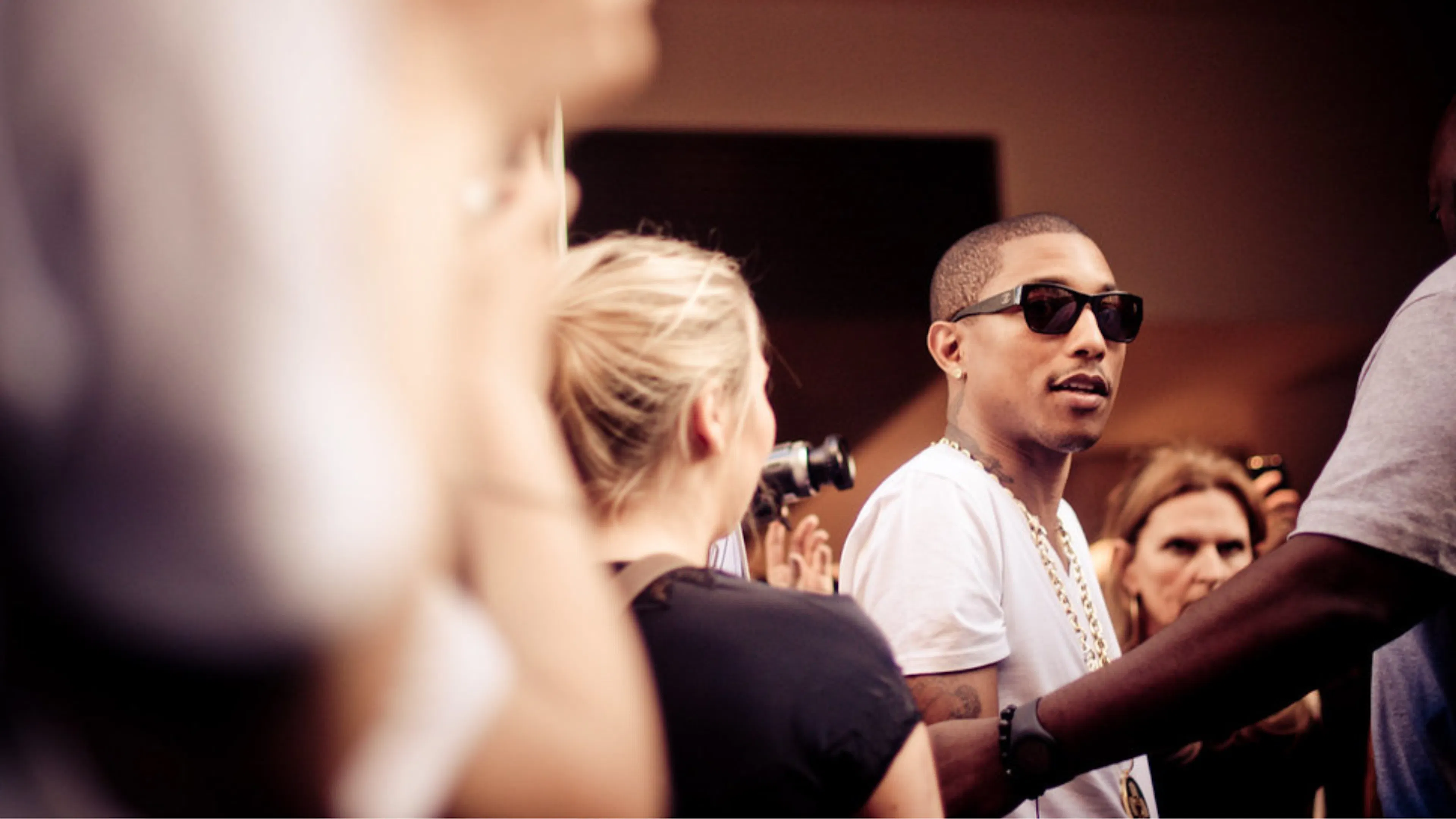 Pharrell Williams with sunglasses on surrounded by crowd