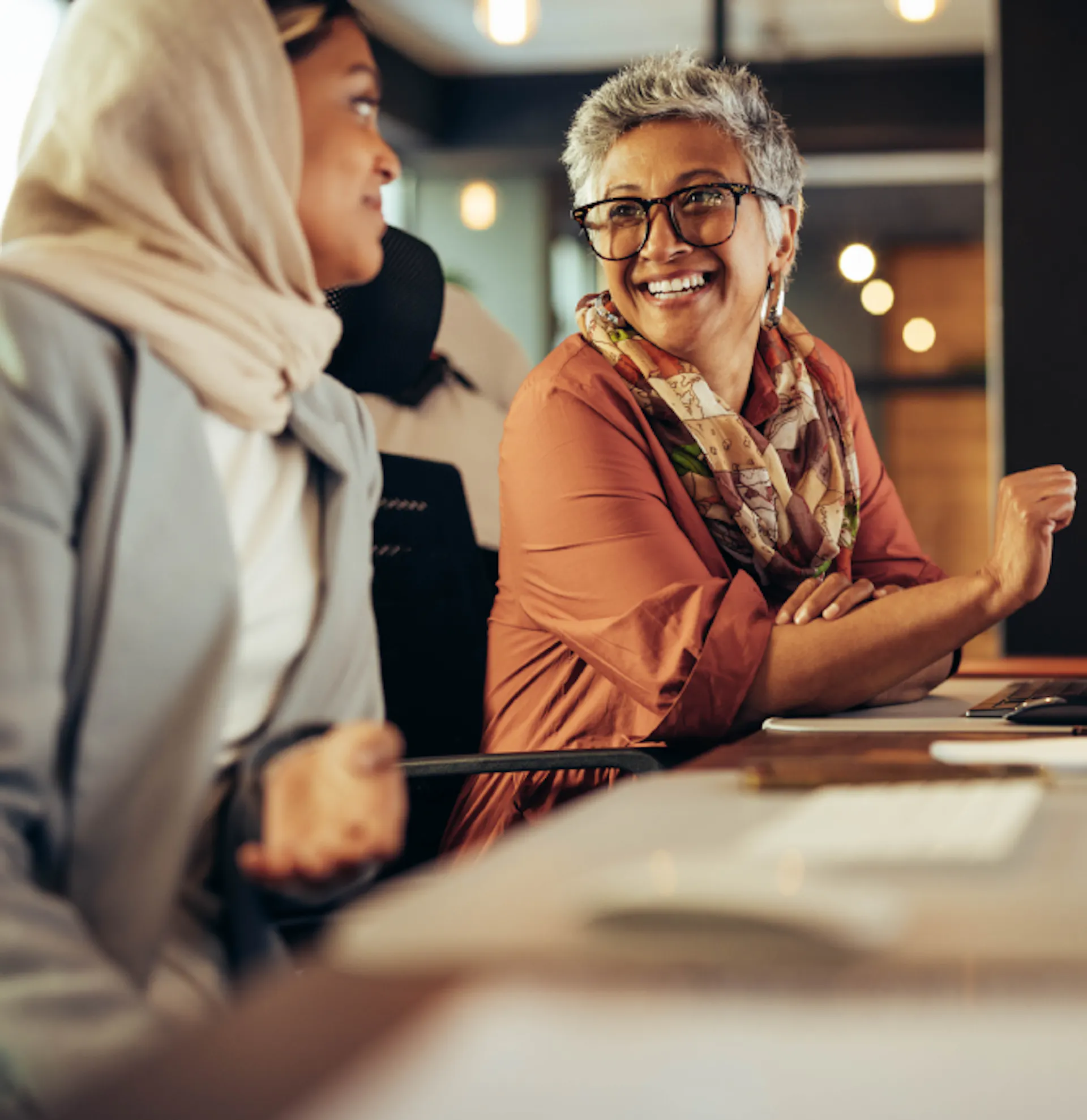 Two diverse office workers smiling at each other. 