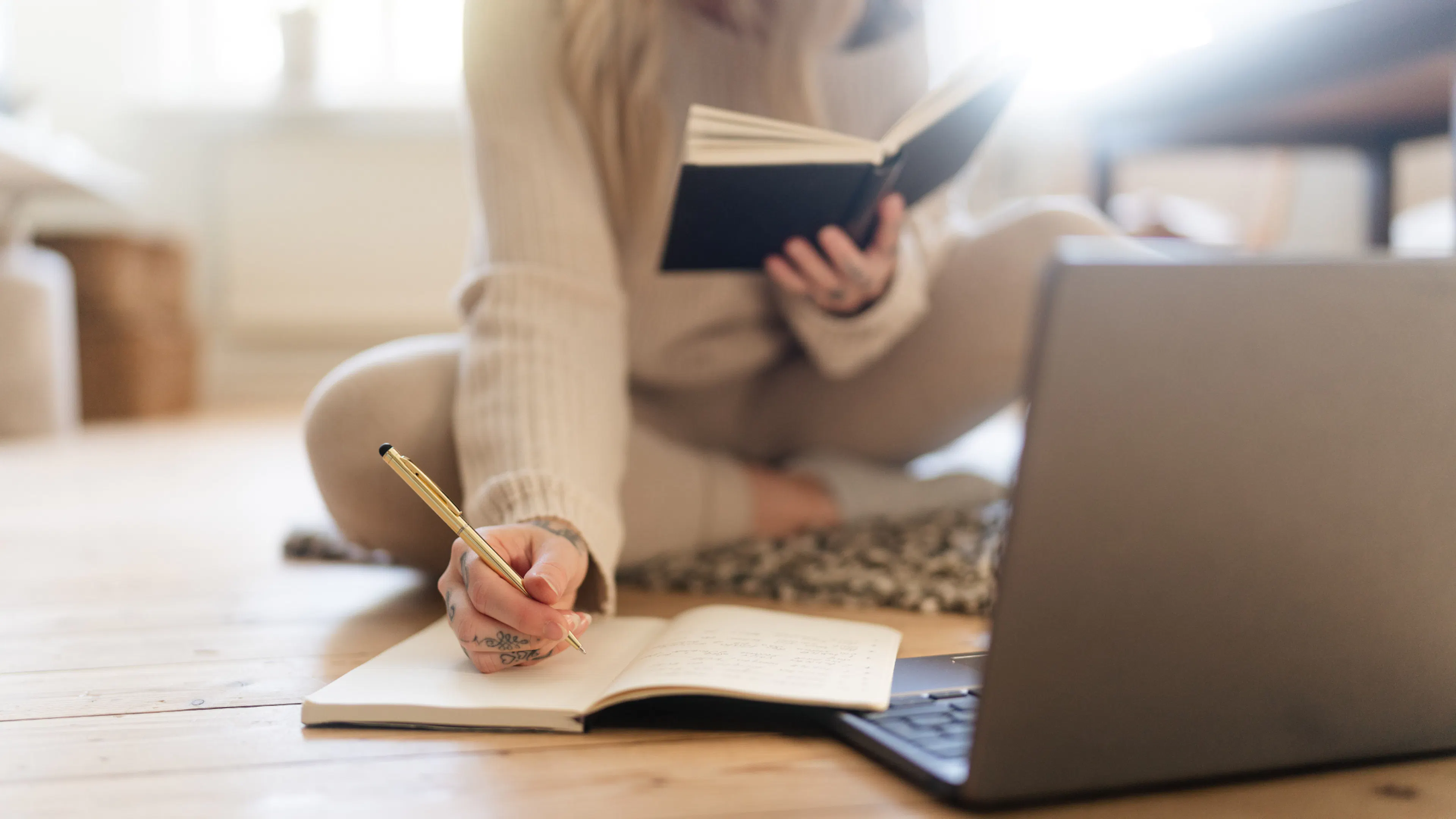 woman sat on floor with books and laptop