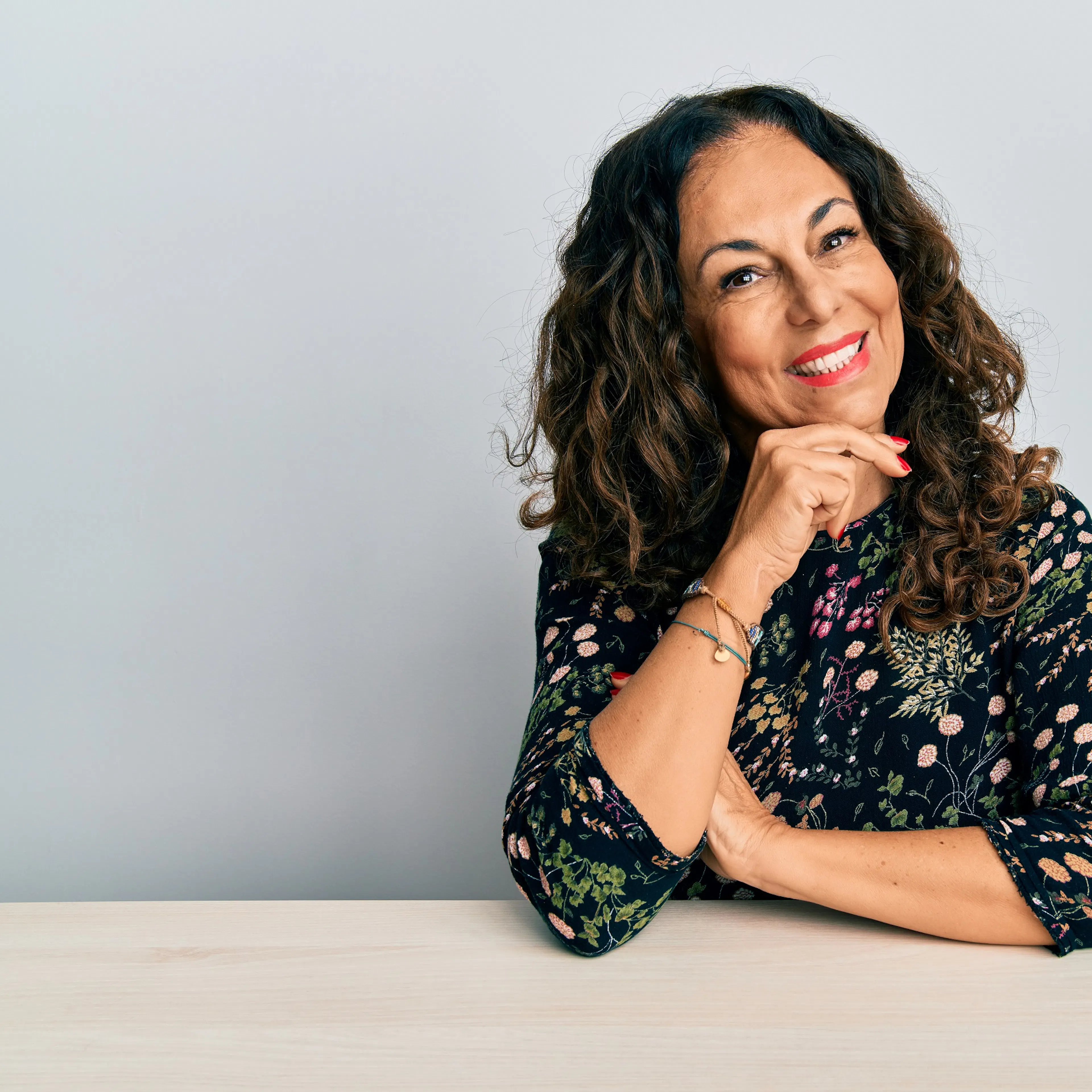 mature woman smiling at camera with chin rested on hand
