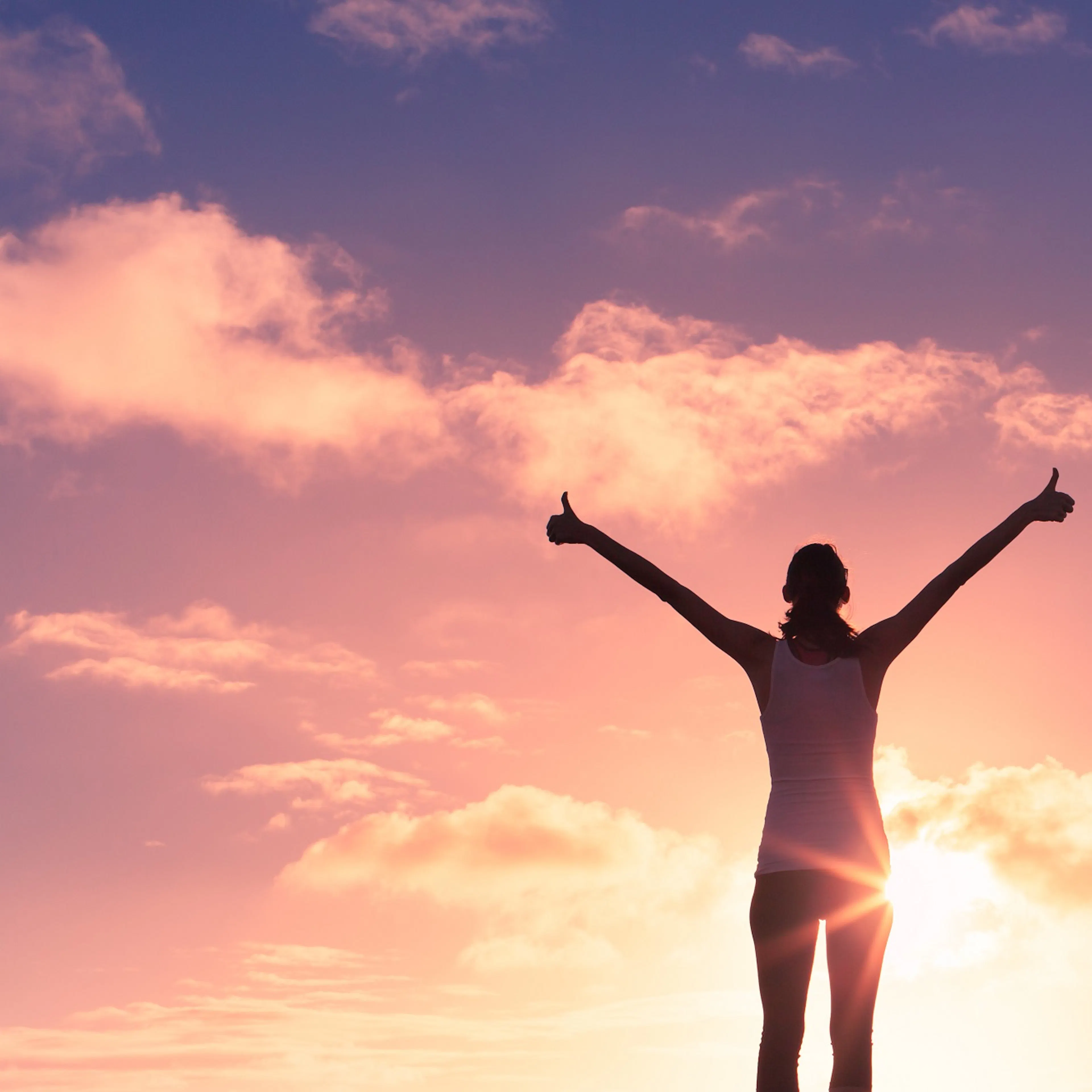 woman in exercise clothes giving double thumbs at sunrise 