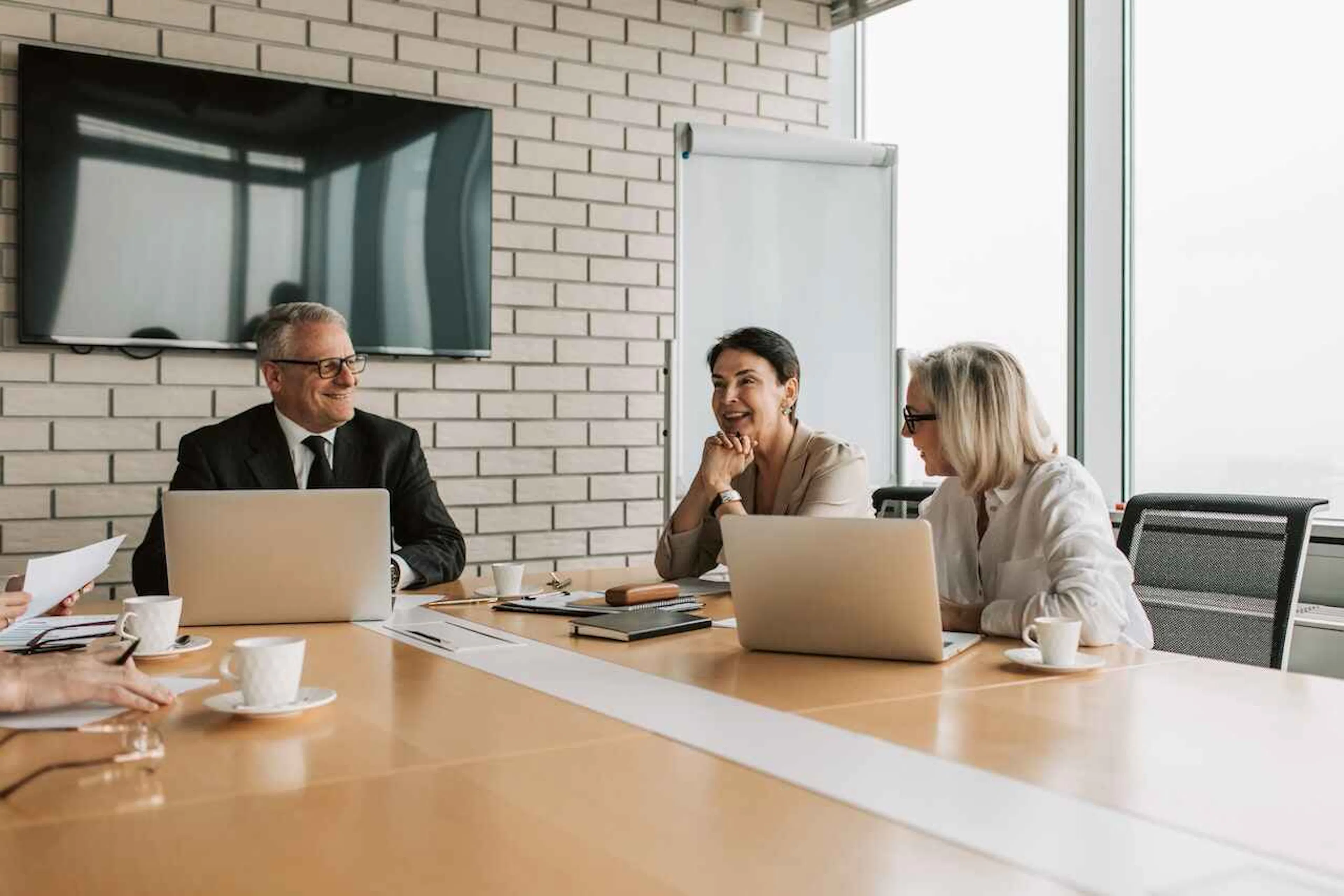 One man and two women sitting at a boardroom table