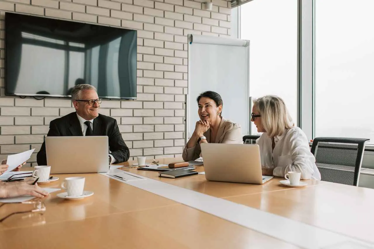 One man and two women sitting at a boardroom table