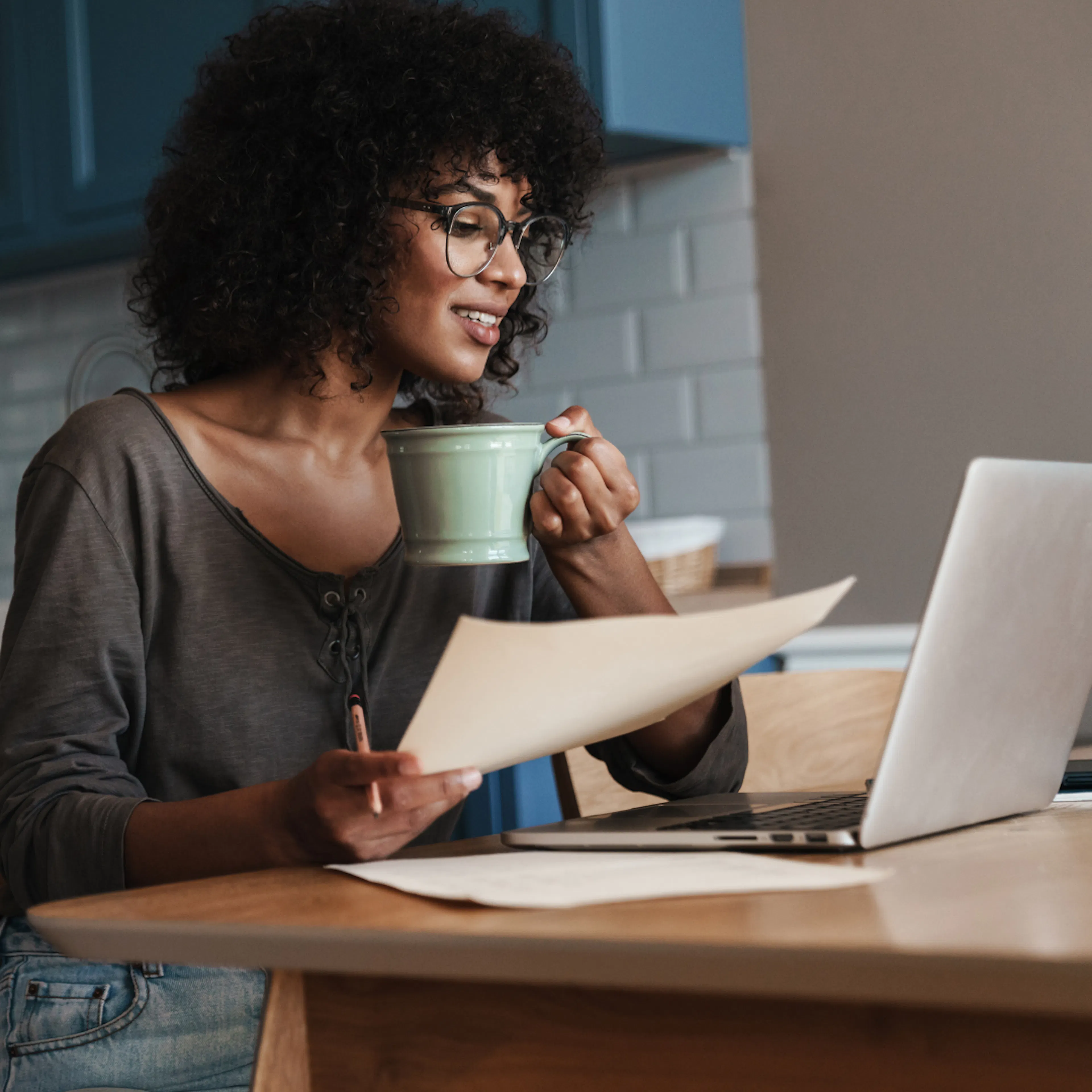 Female working from kitchen table with laptop and paperwork 