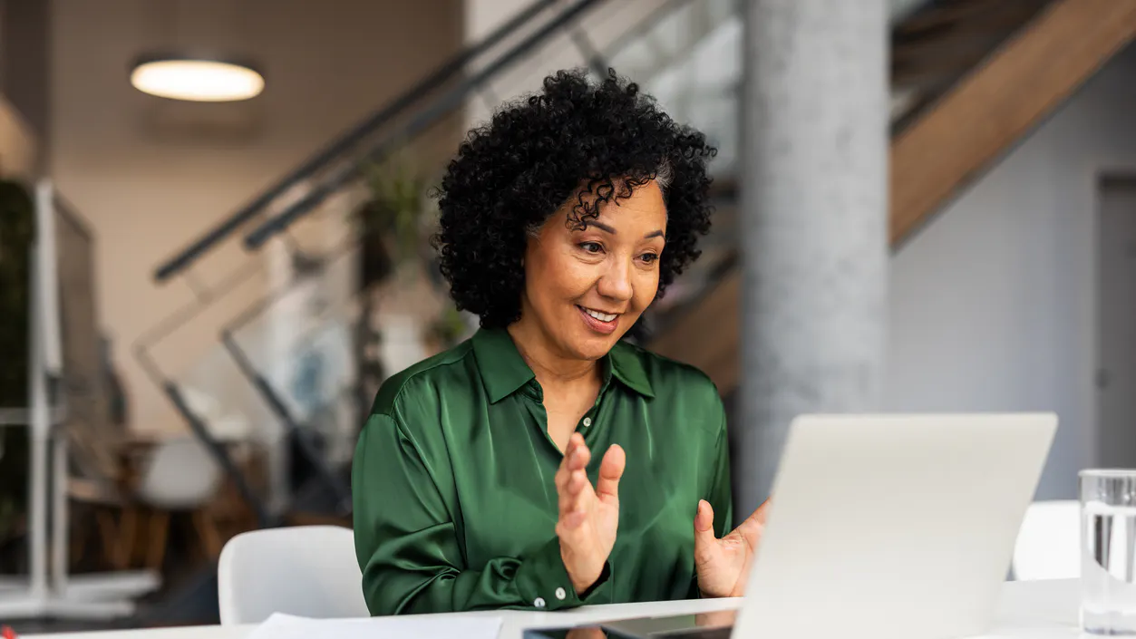 woman green shirt dark hair at laptop smiling