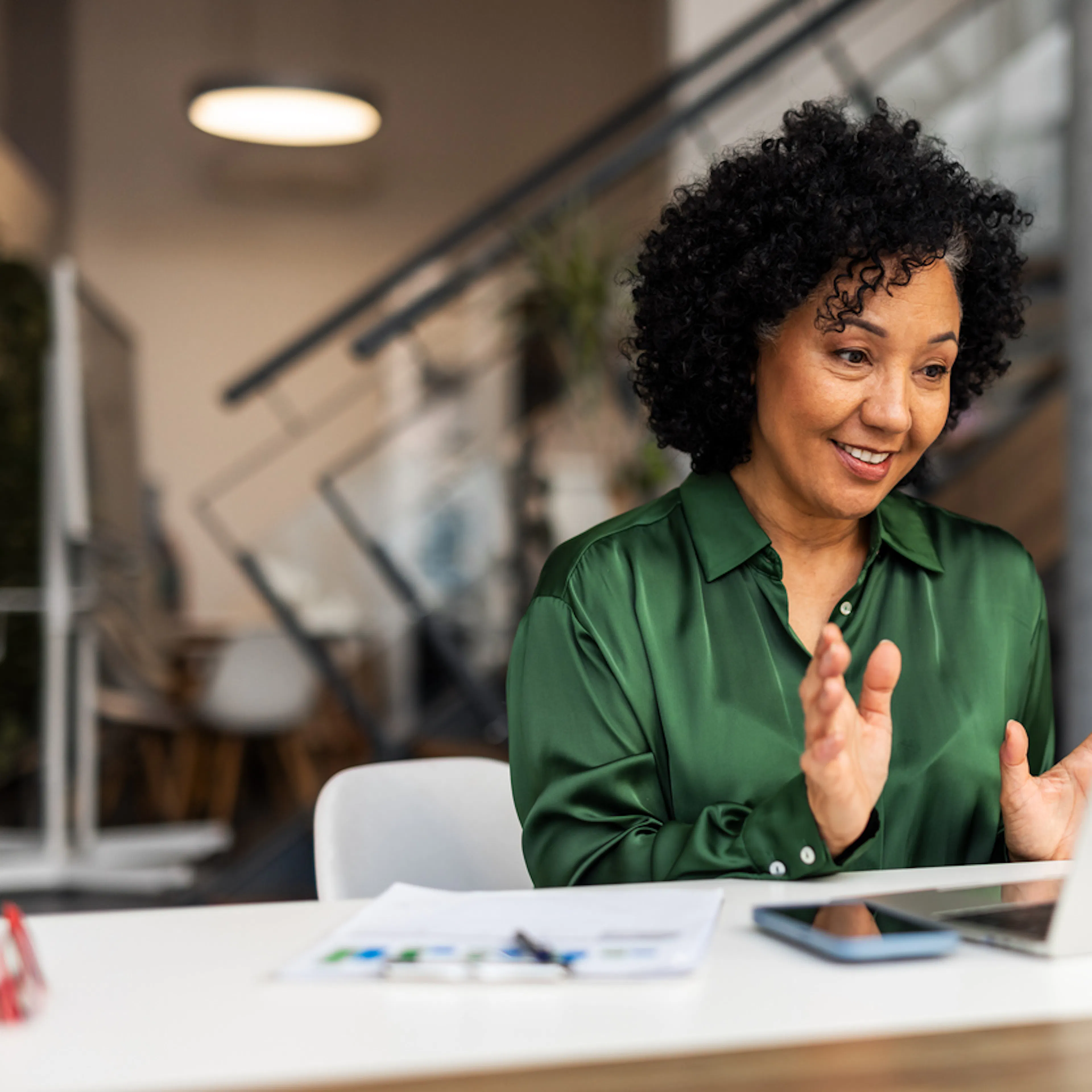 woman green shirt dark hair at laptop smiling