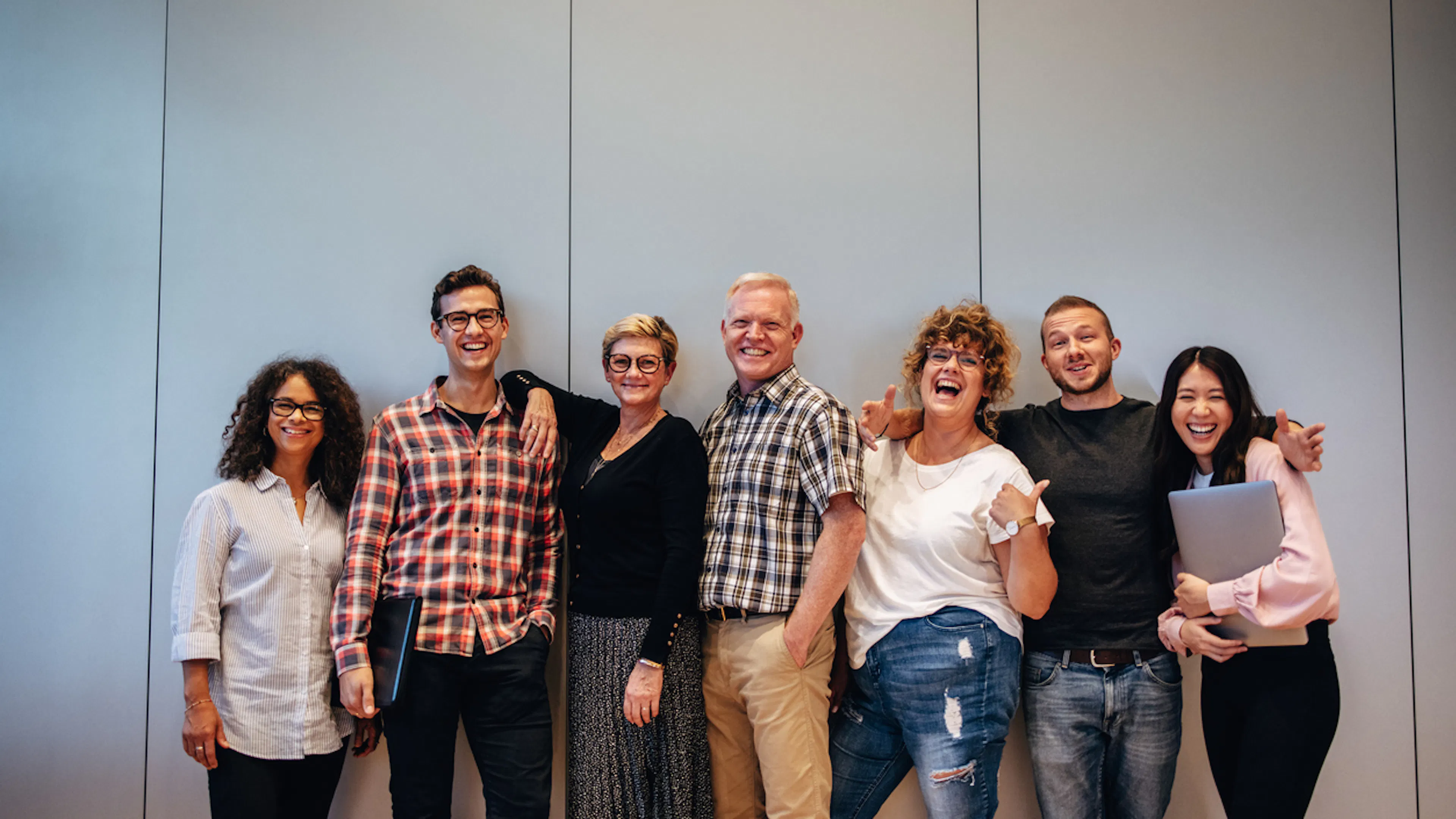 Men and women standing against a wall happy