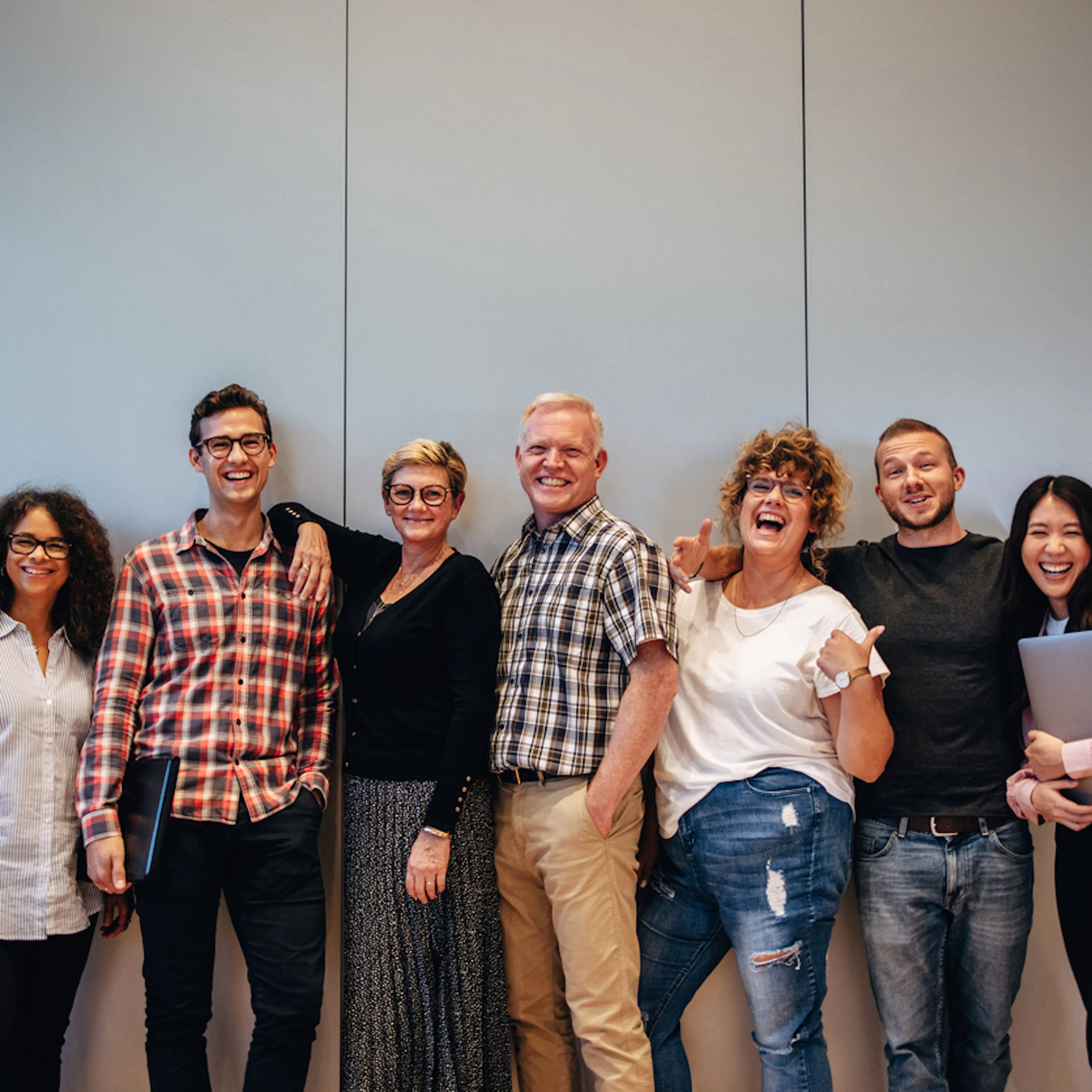 Men and women standing against a wall happy