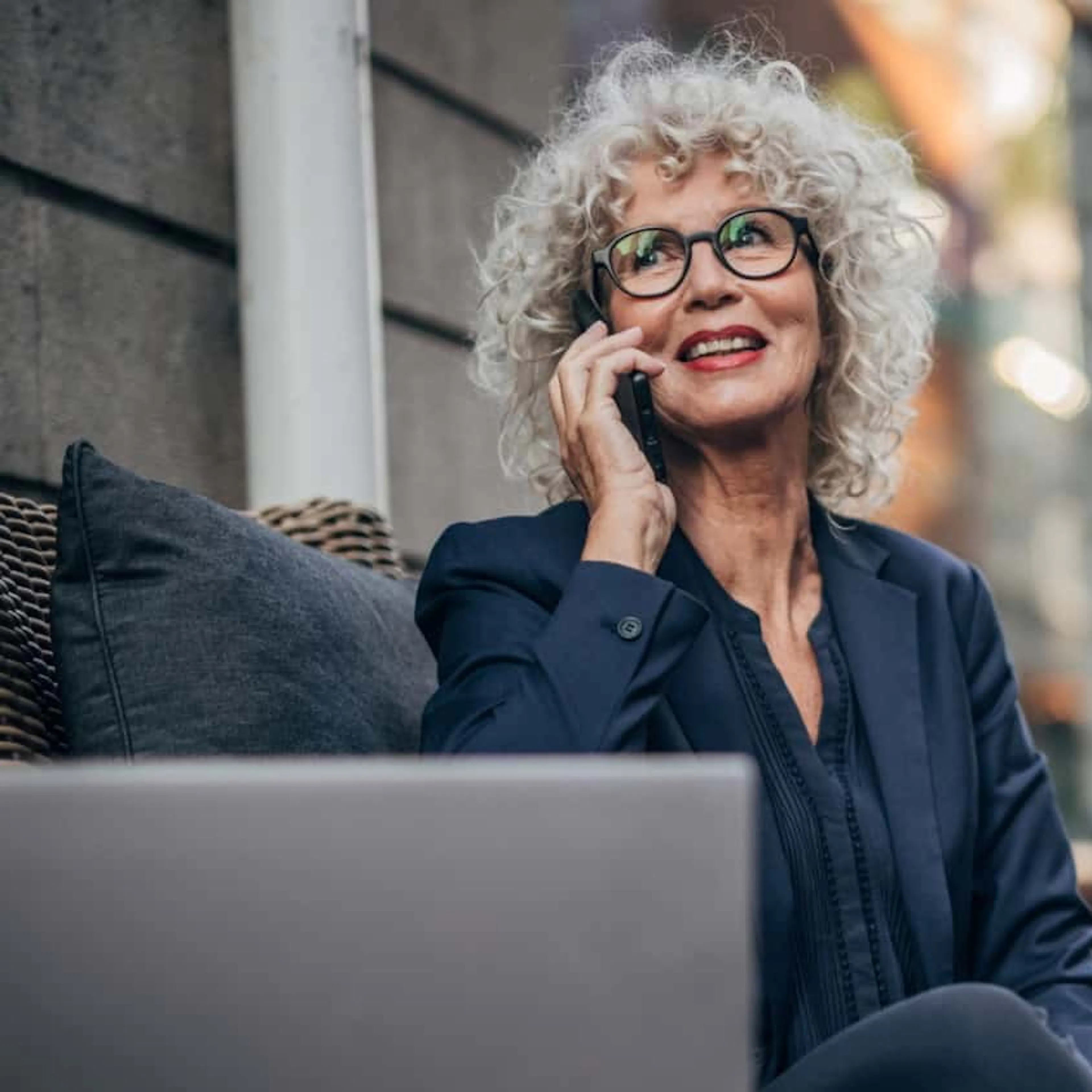 50 something female wearing grey suit and on phone