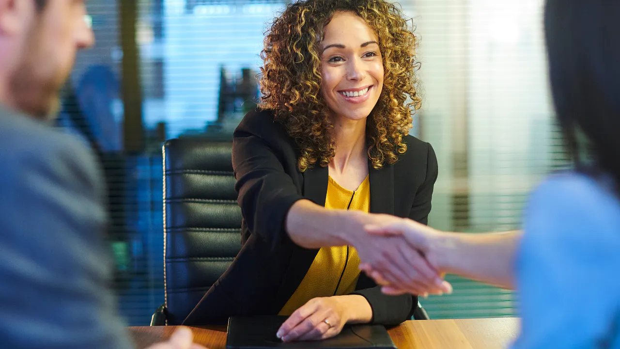 Woman smiling and shaking hands of her interviewers