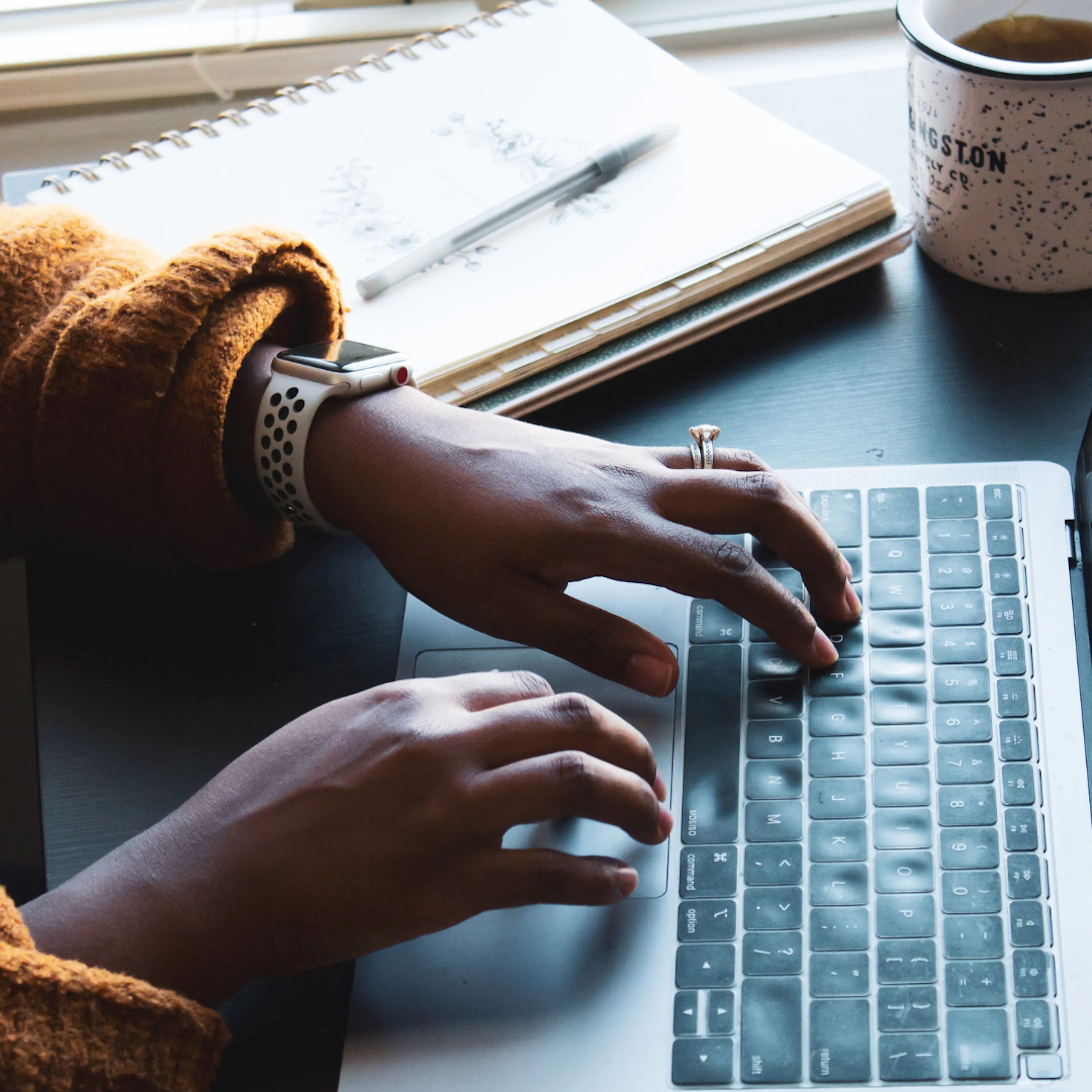 close up of black persons hands using a laptop