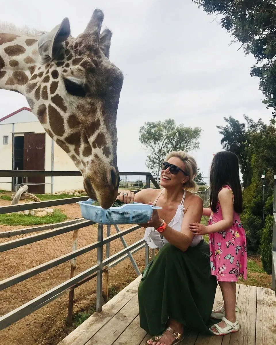 Hannah with her daughter feeding a giraffe