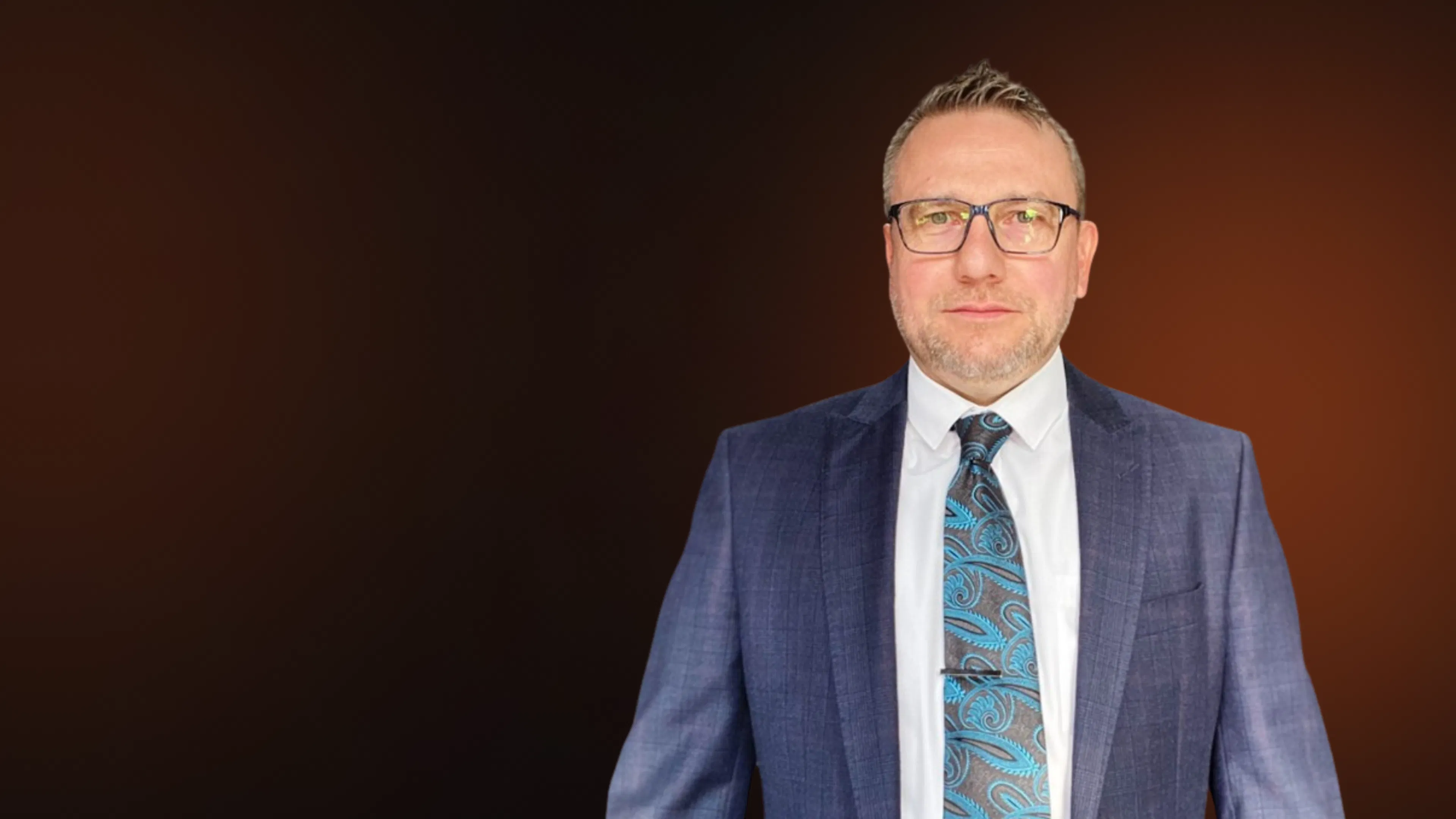 Head and shoulders portrait of Darren Underhill, wearing a suit and tie.