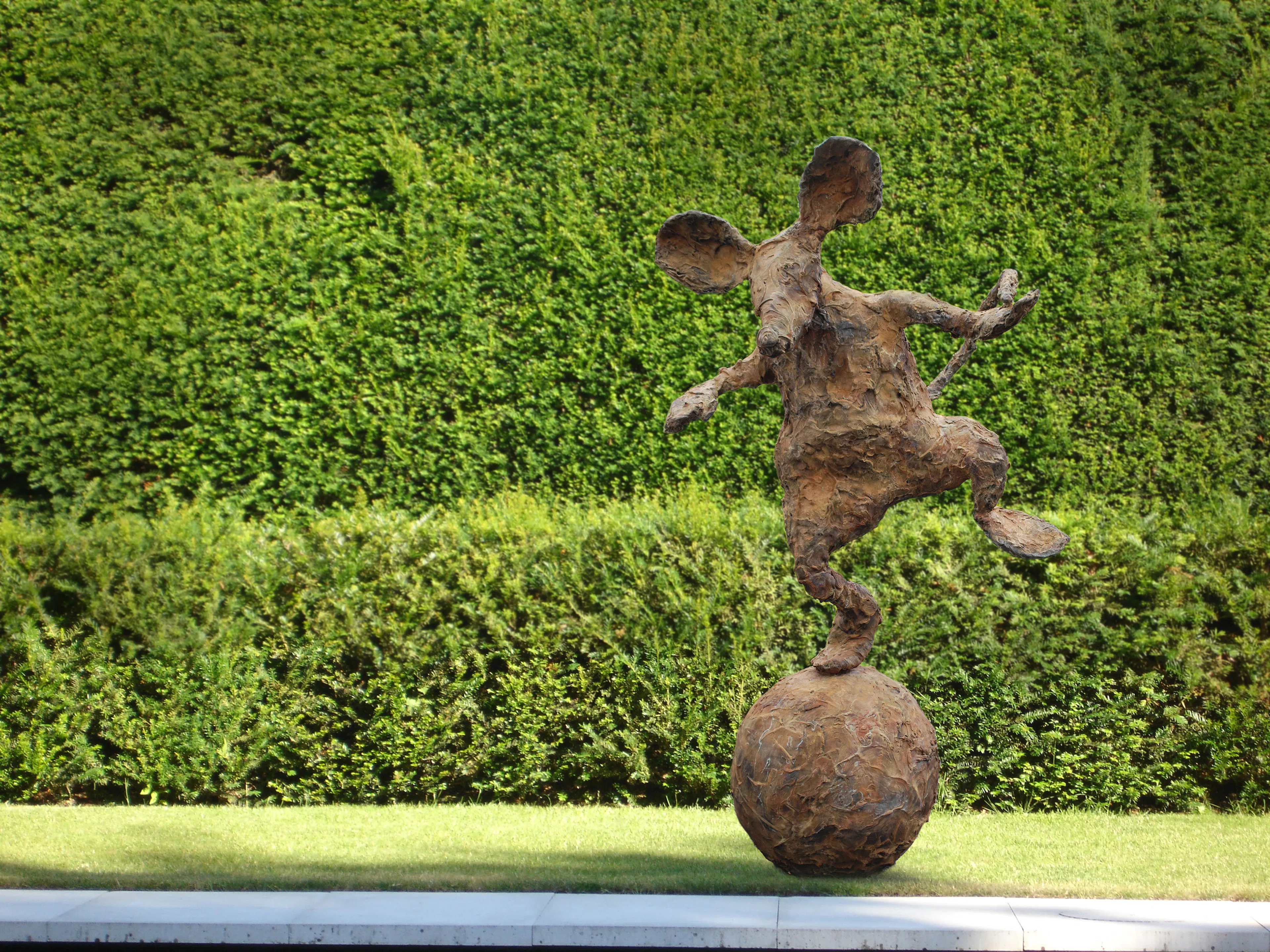 A sculpture of a mouse on a ball.