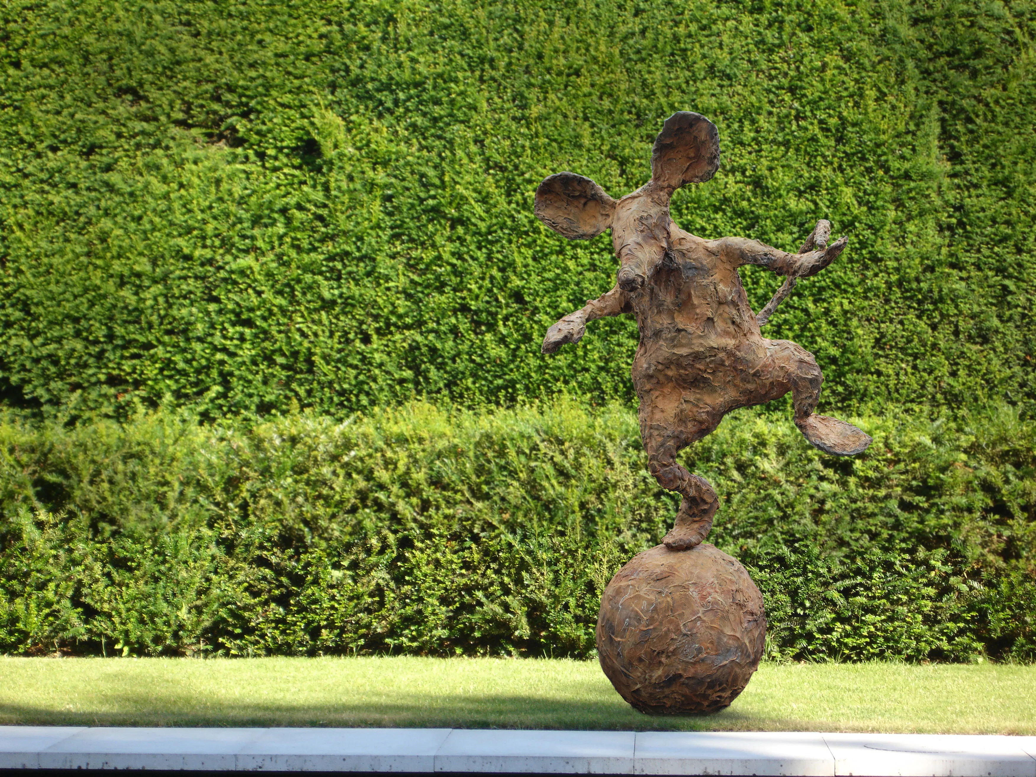 A sculpture of a mouse on a ball.