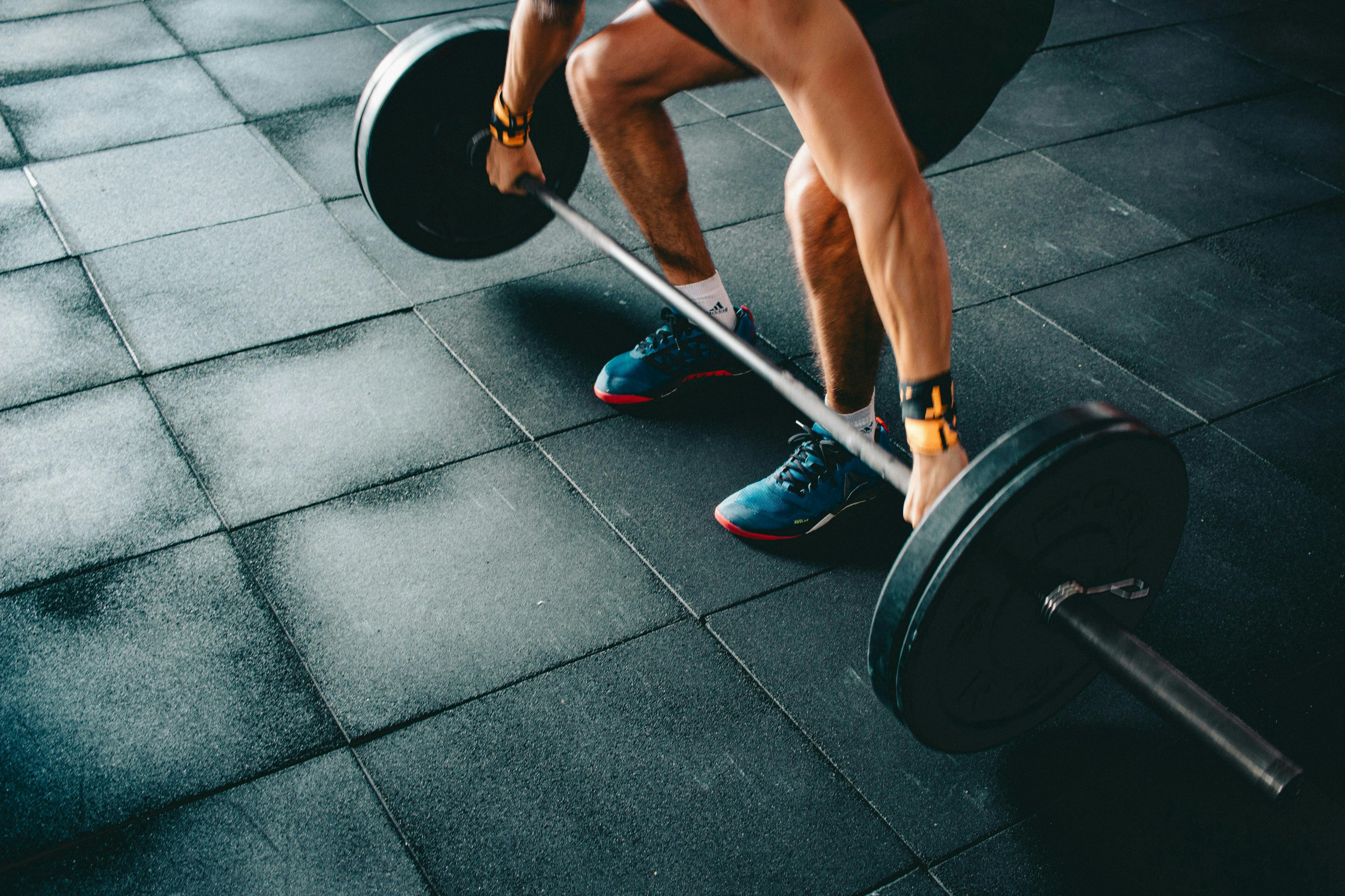 A man standing in front of a barbell in a squat position, getting ready to do a snatch. 