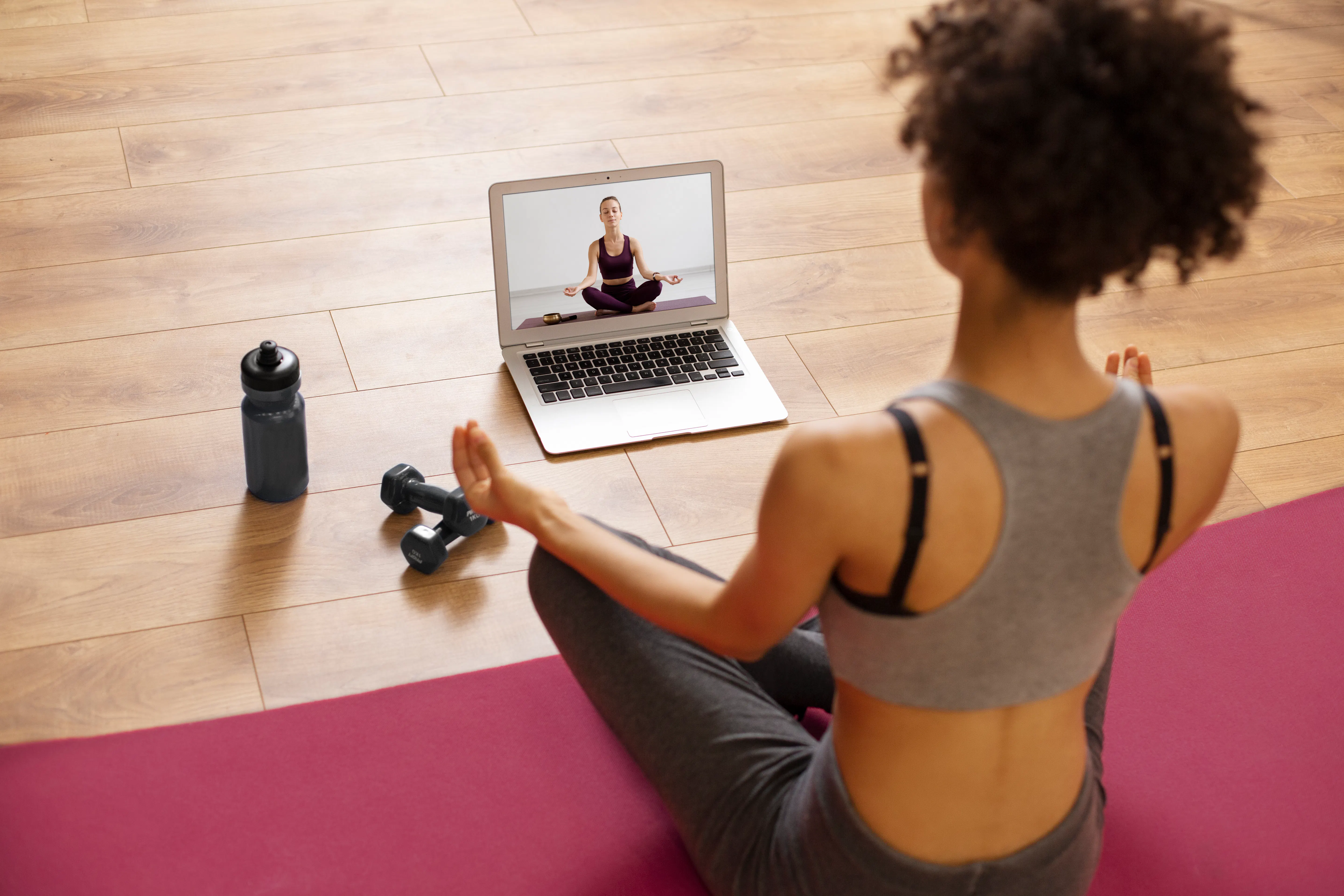 A woman is doing yoga via an online video.